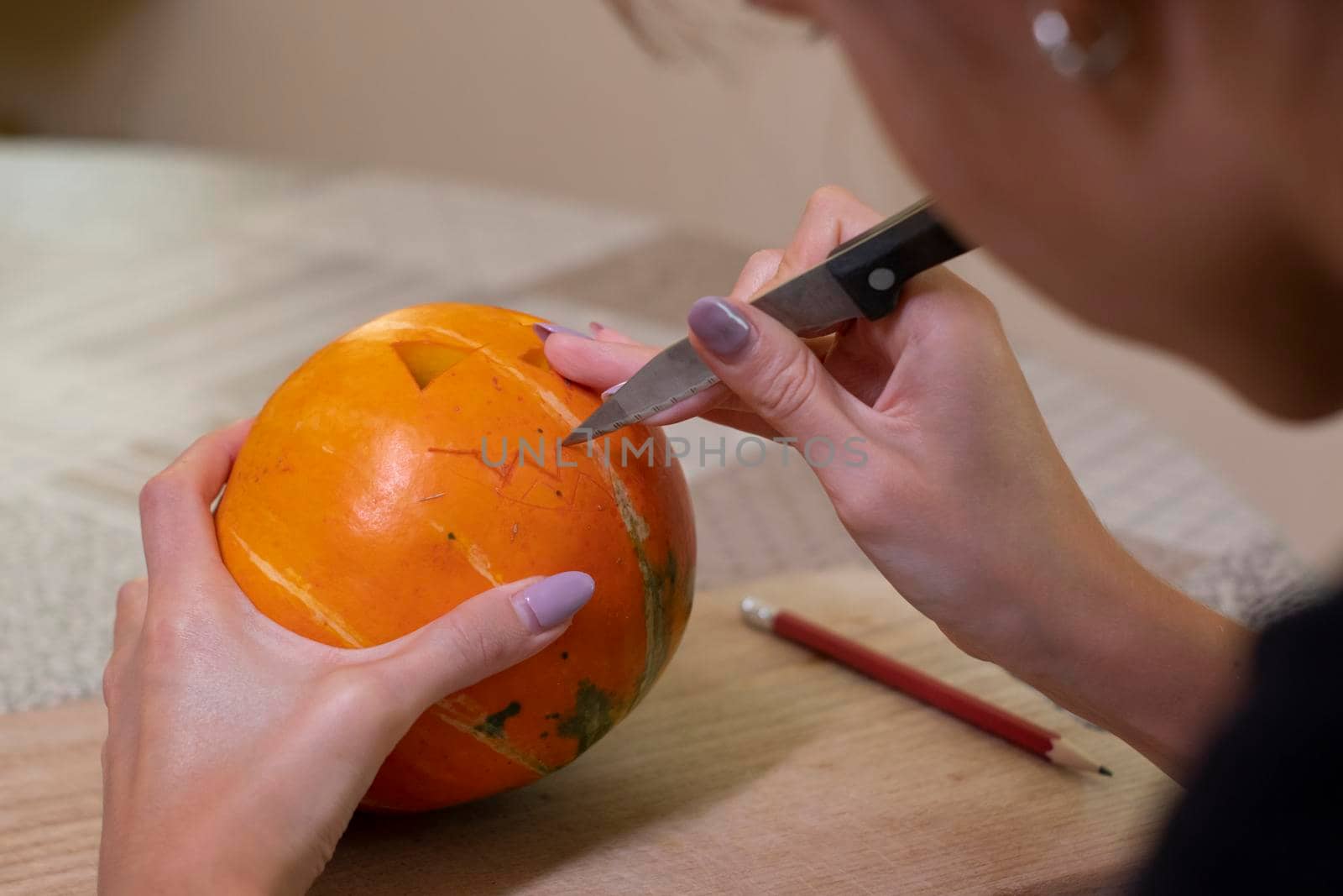 the process of making a Halloween pumpkin. cutting out the mouth by brunette girl. horror theme and Hallowe'en.