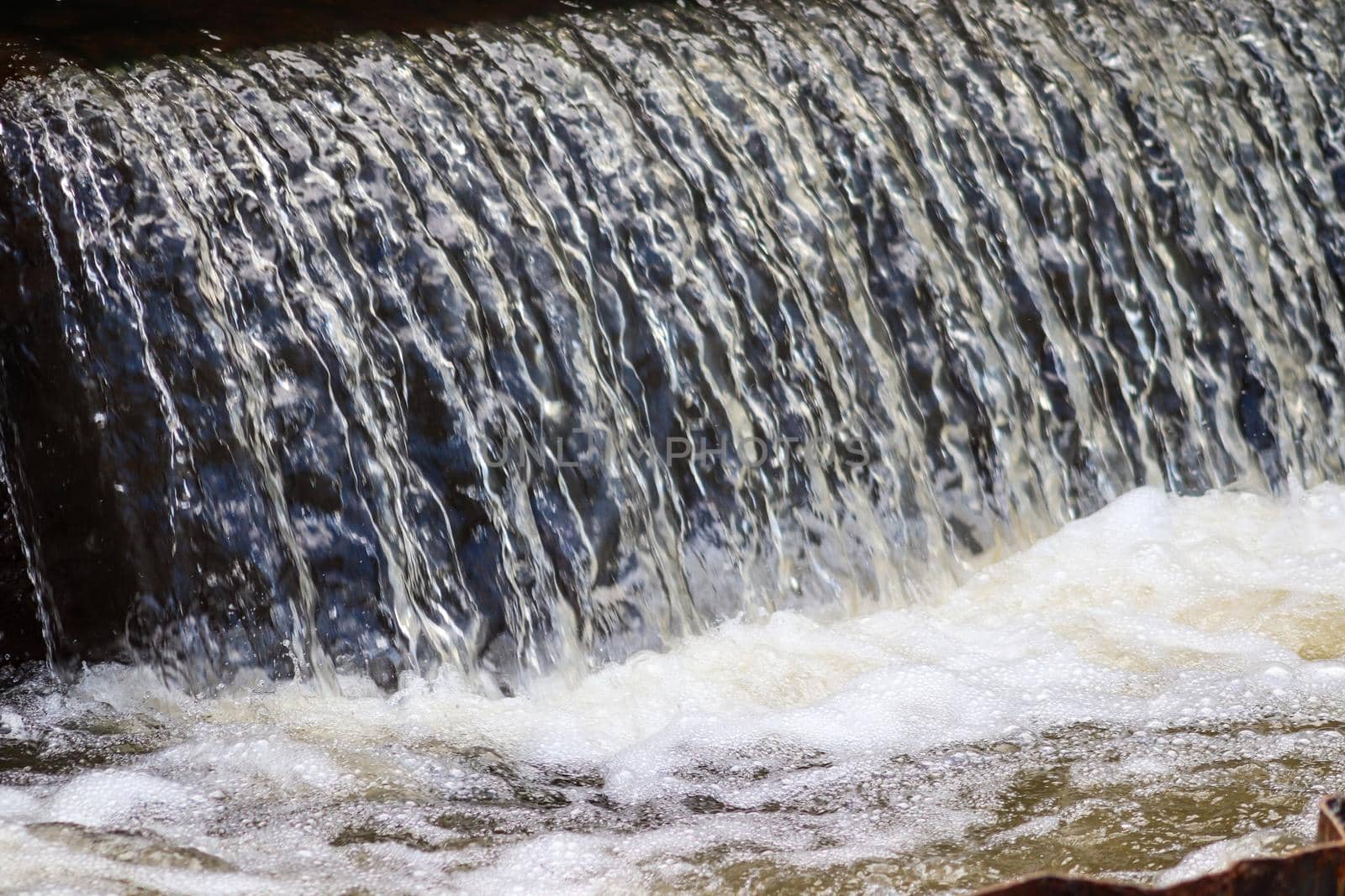 close up of a small waterfall under a bridge. High quality photo