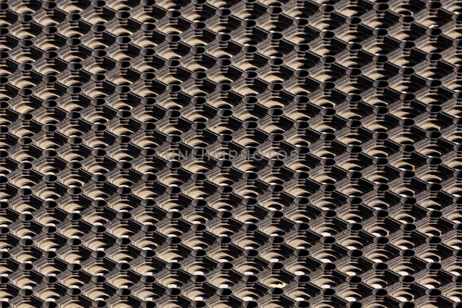 texture and background of used dusty cellular rubber floor mat - aligned perspective view