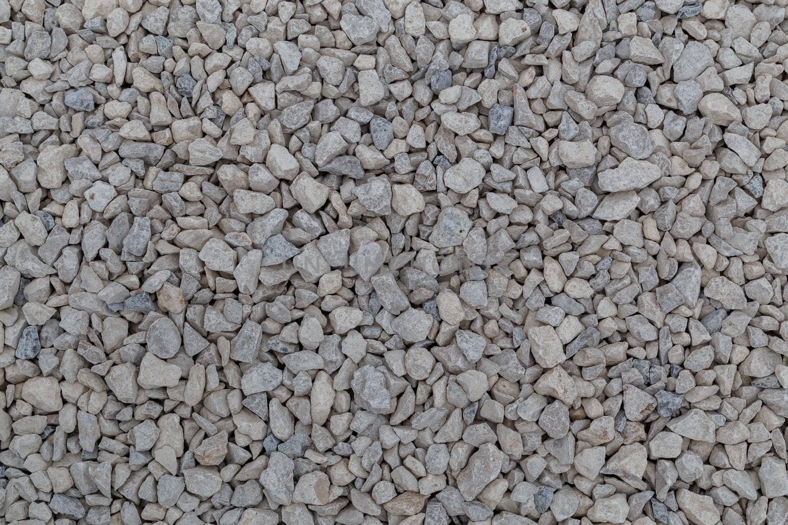 Dry white limestone ballast flat full frame background. Small gray dusty broken macadam stones texture. Viiew from above.