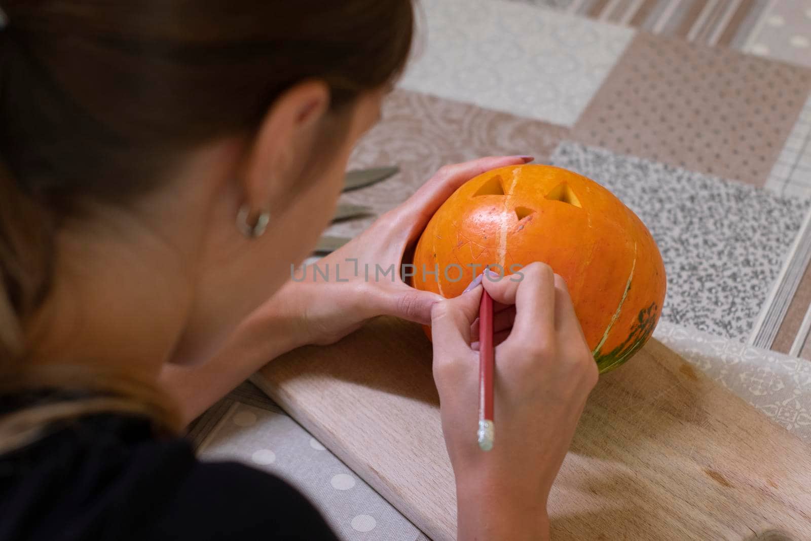 the process of making a Halloween pumpkin. drawing a layout by a brunette girl. horror theme and Hallowe'en by oliavesna