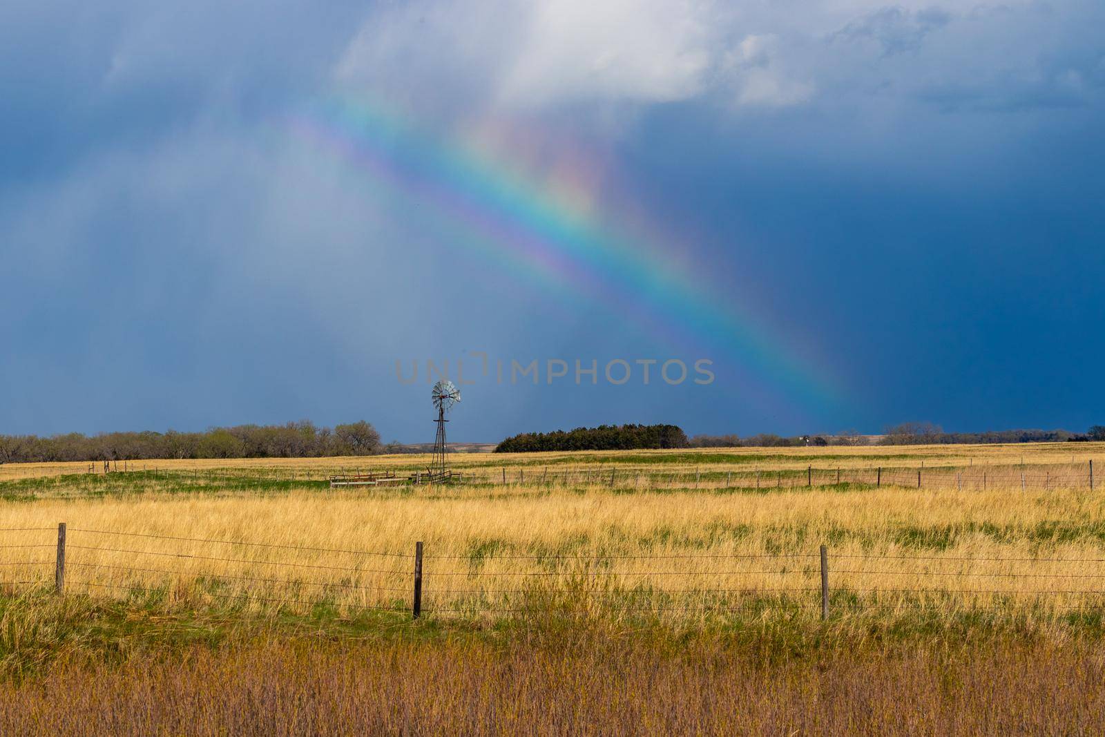 Nature Rainbow over pretty green Nebraska landscape with windmill. High quality photo