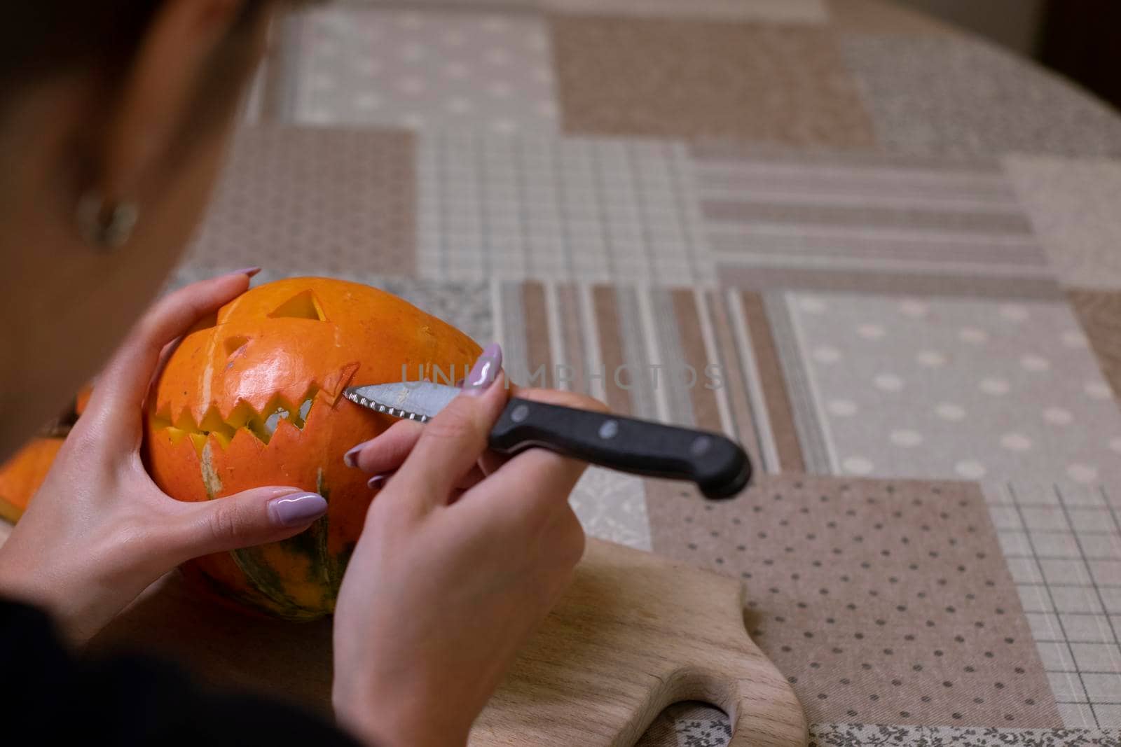 the process of making a Halloween pumpkin. cutting out the mouth by brunette girl. horror theme and Hallowe'en.