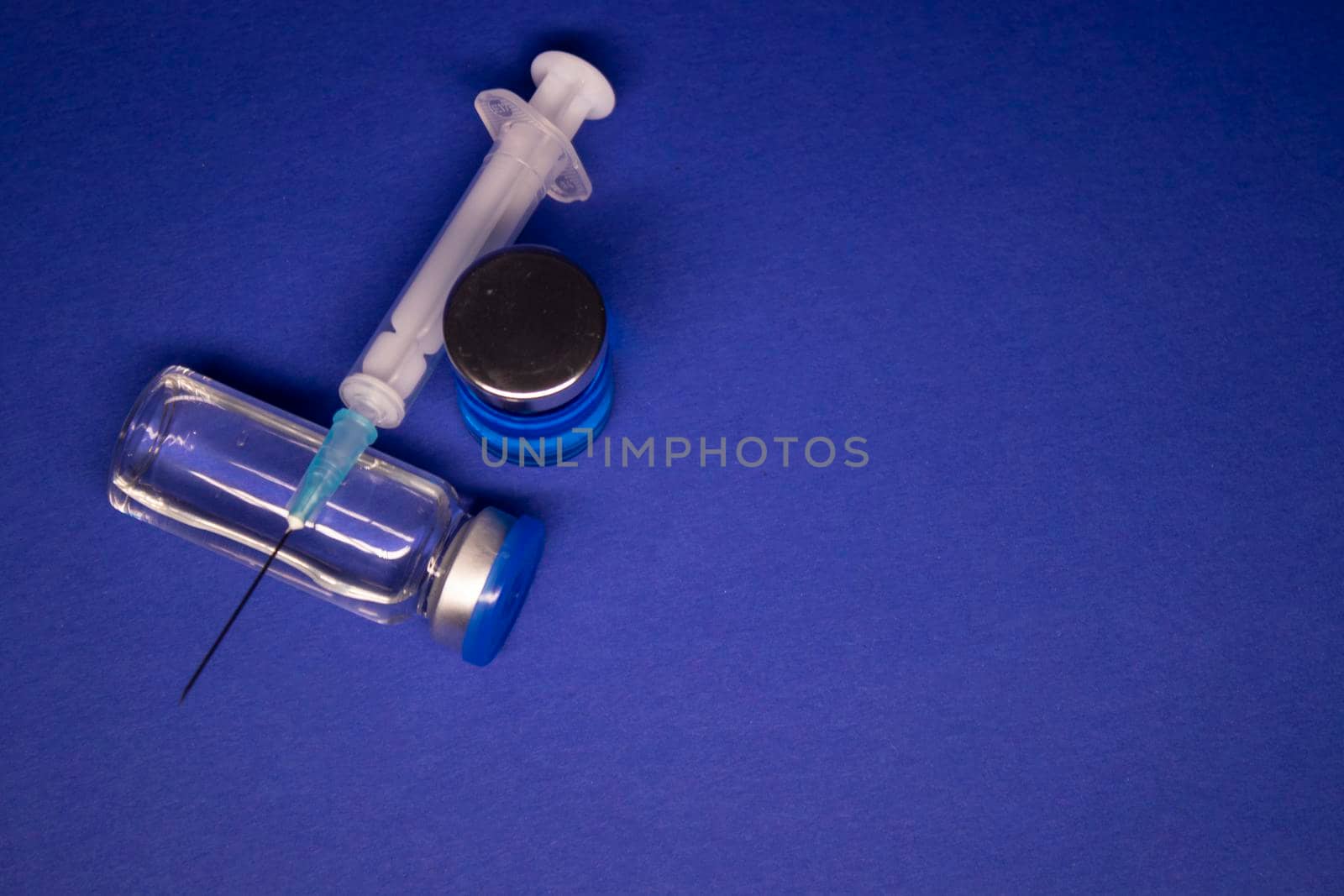 two transparent Vaccine bottle phial with no label, medical syringe injection needle. isolated on blue background. Development of coronavirus vaccine COVID-19. World race in researching. copy space