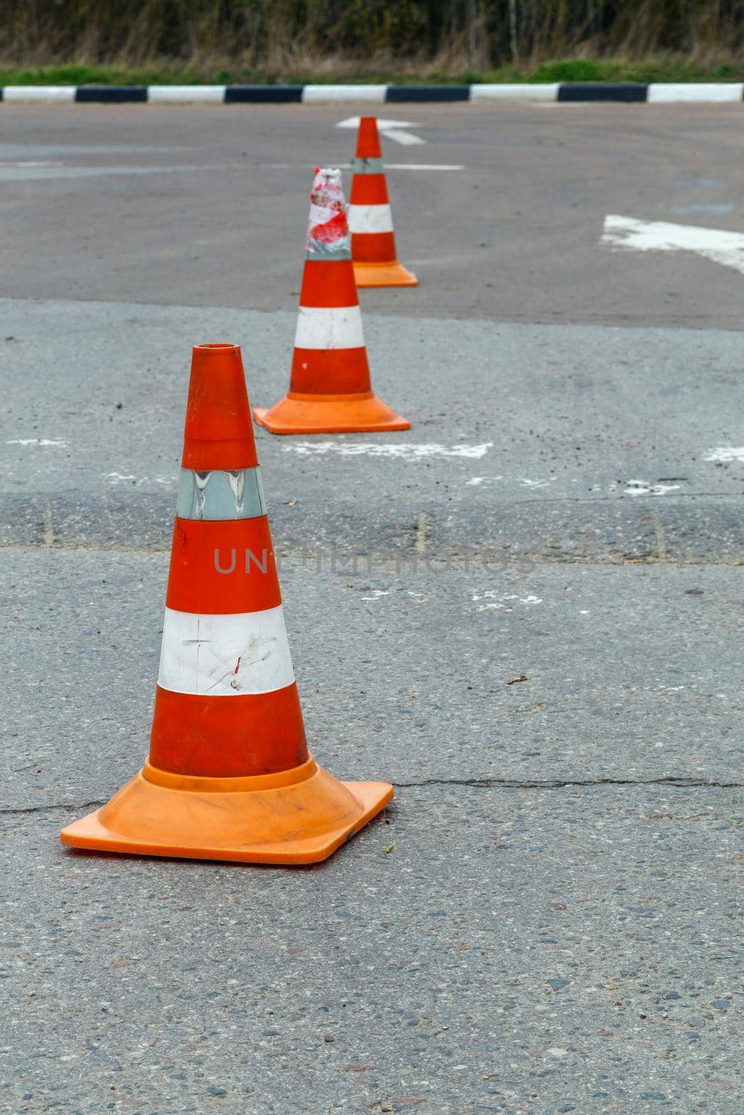 orange traffic cones on dry gray asphalt road surface - close-up with selective focus.