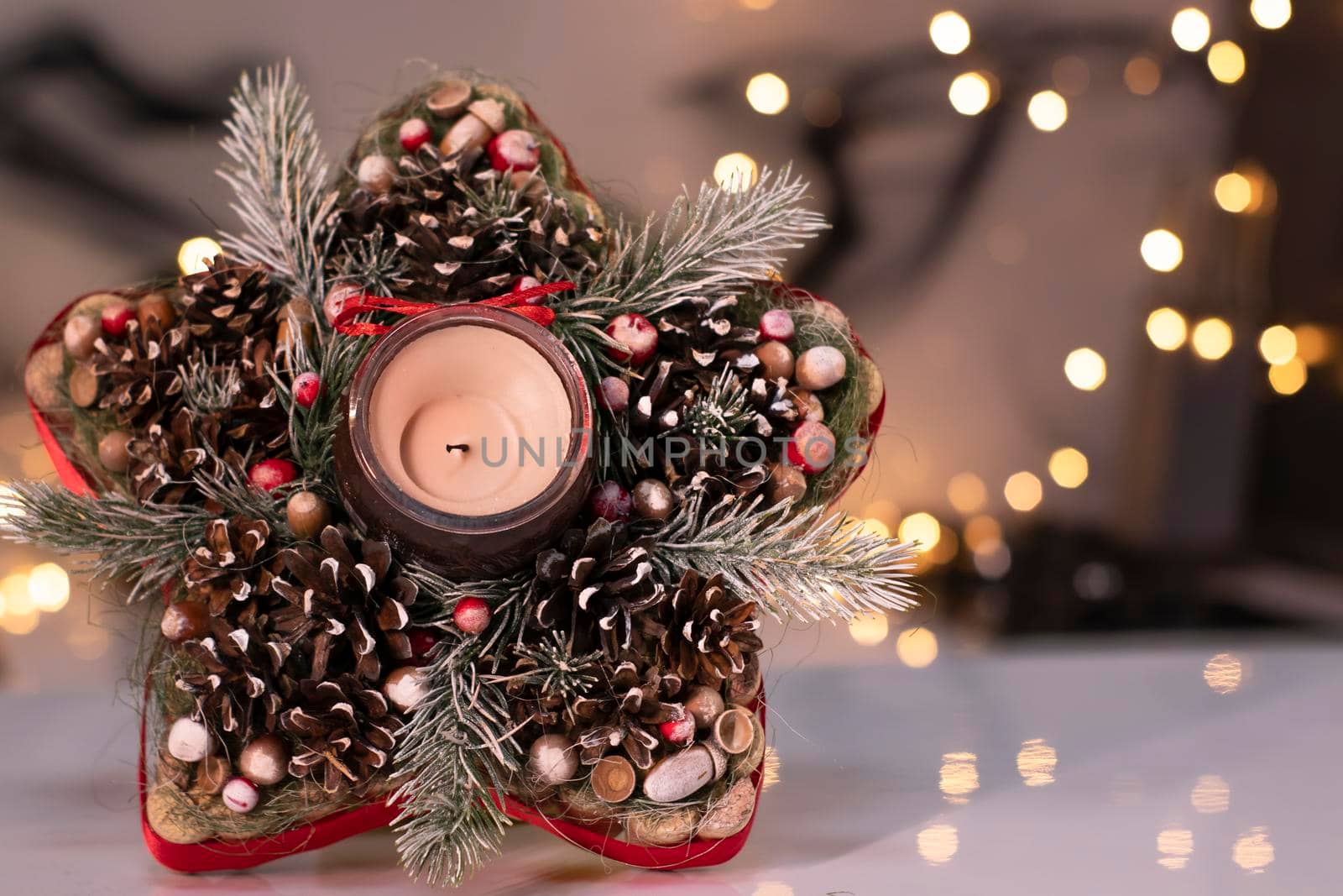 Christmas decor star-shaped made of tree branch with new years toys on it and a candle in it by oliavesna