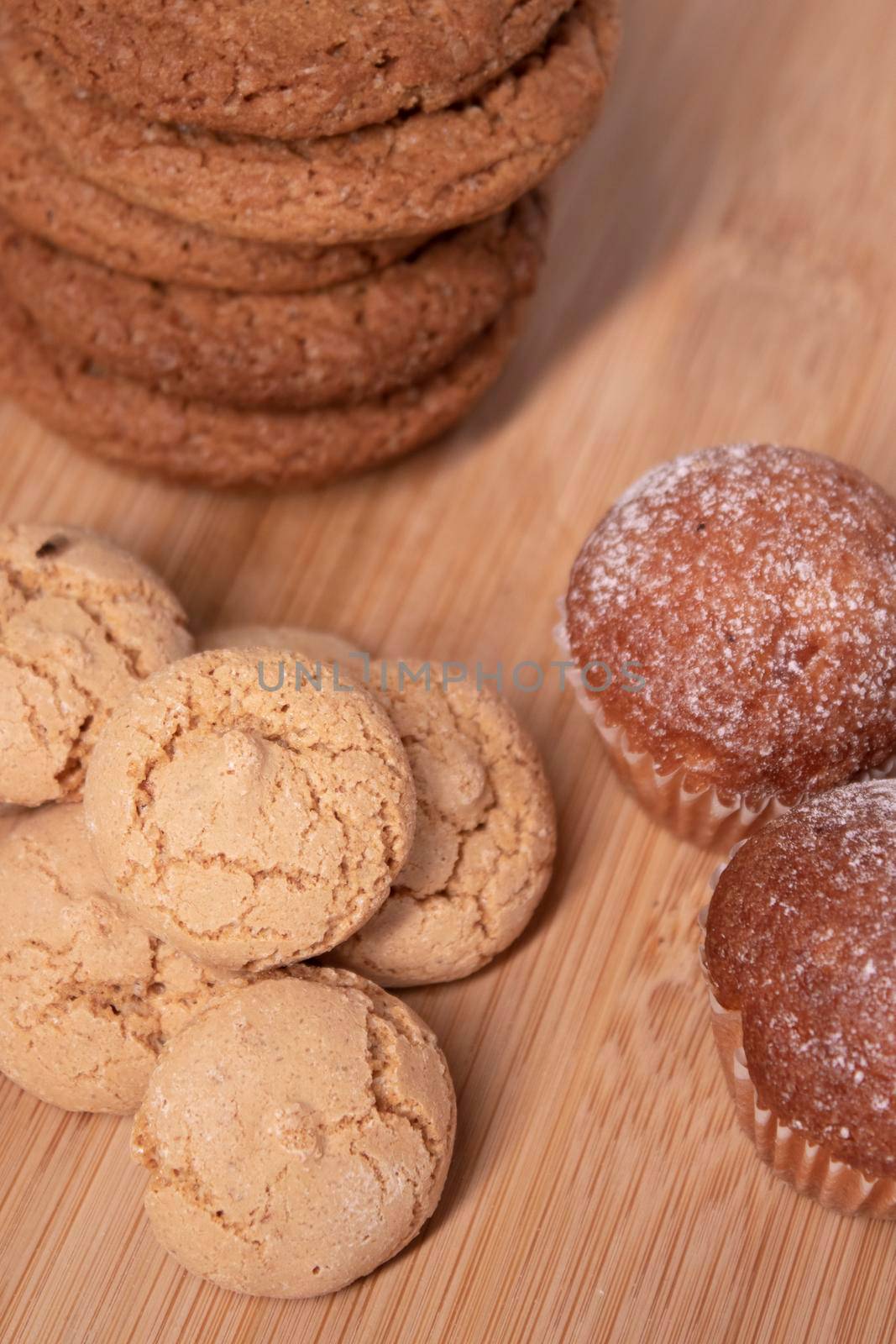 muffins, almond amaretti and oat cookies on wooden stand board. sweet bakery concept by oliavesna