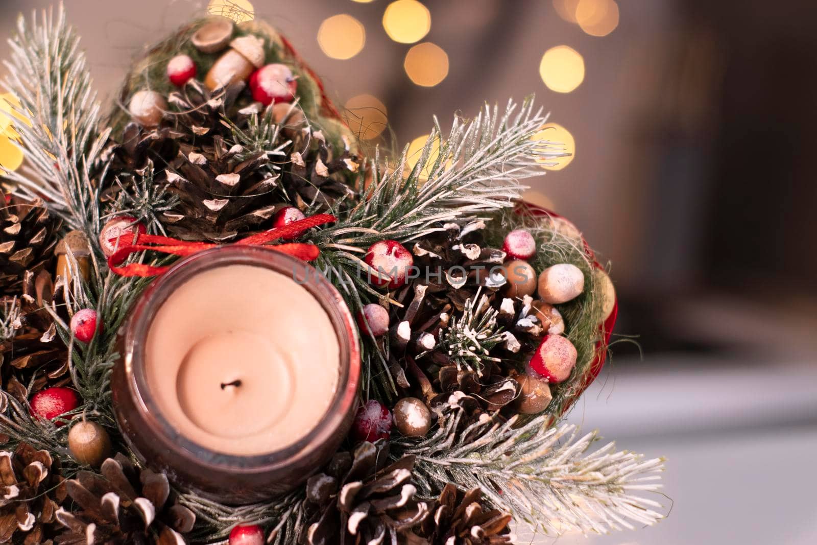 Christmas decor star-shaped made of tree branch with new years toys on it and a candle in it.