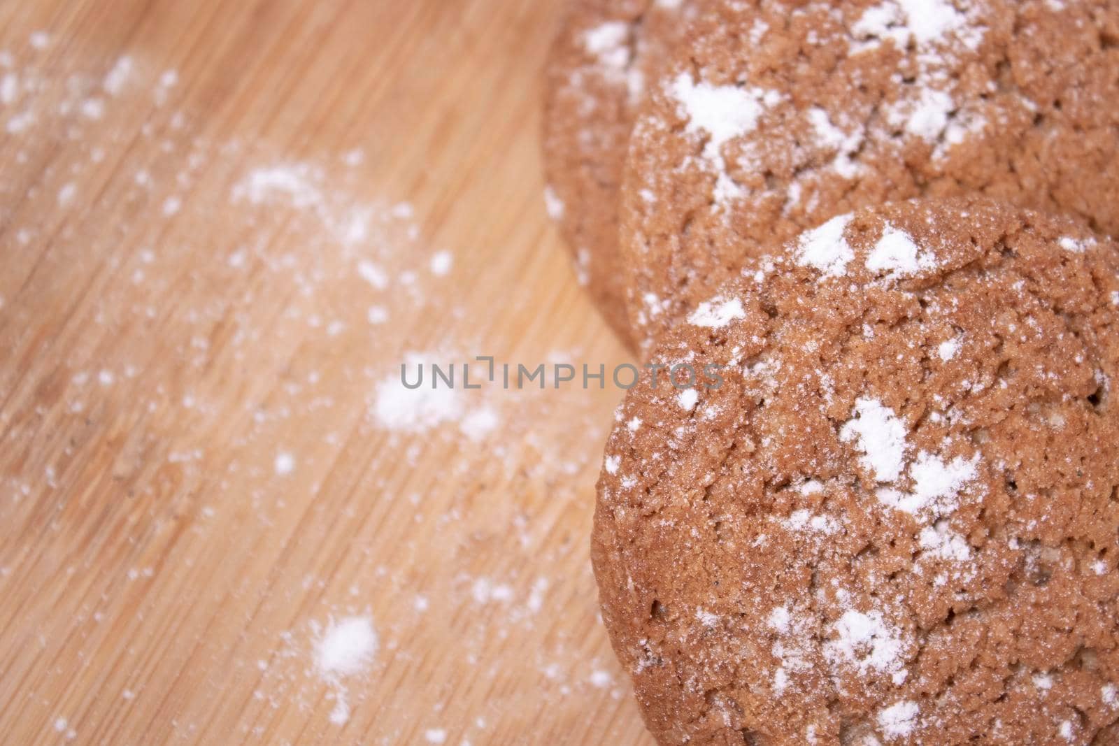oatmeal cookies covered in powdered sugar on wooden stand board. sweet bakery concept by oliavesna