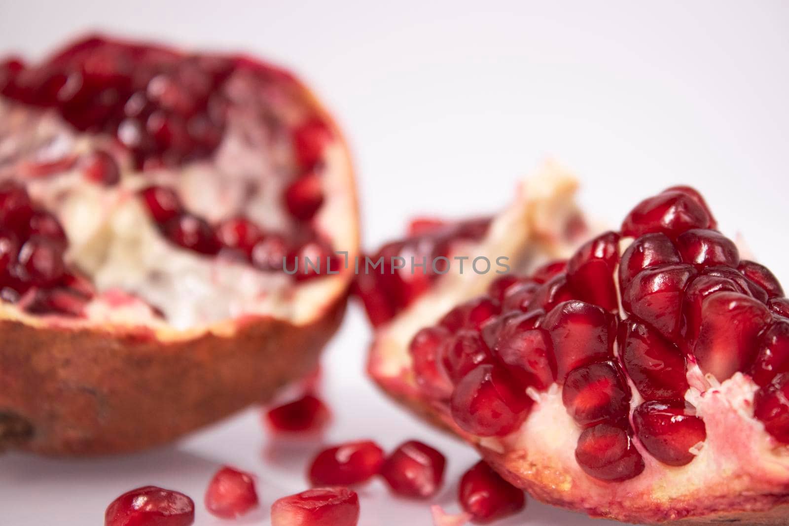 ripe fresh sliced pomegranate fruit with red seeds isolated on white background