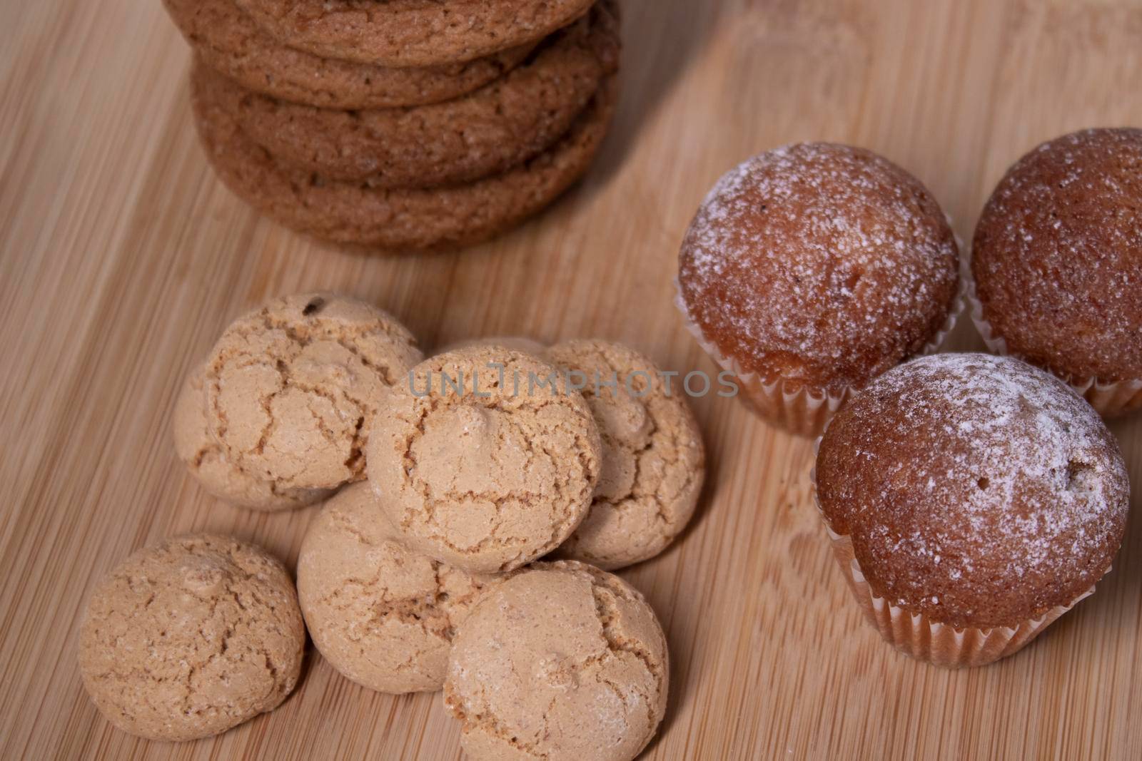 muffins, almond amaretti and oat cookies on wooden stand board. concept of sweet bakery