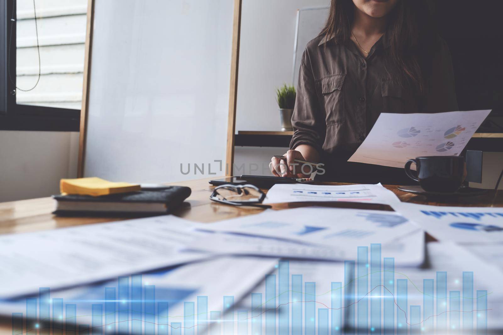 Close up Business woman hand holding pen and calculating with paperwork and virtual stock chart