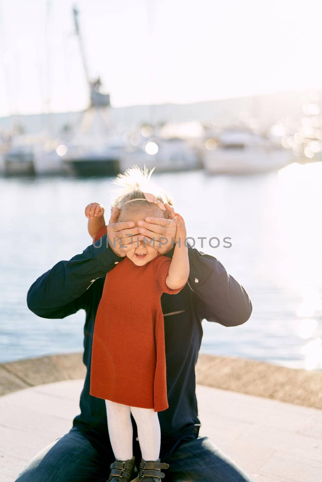Father and daughter are playing peek-a-boo in a marina in Montenegro. High quality photo
