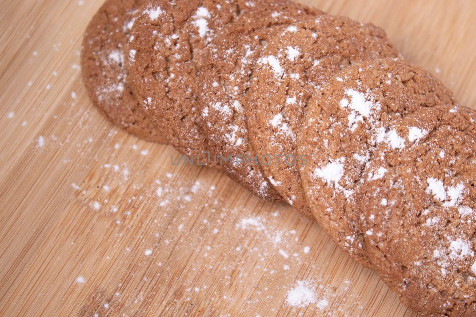 oatmeal cookies covered in powdered sugar on wooden stand board. sweet bakery concept by oliavesna