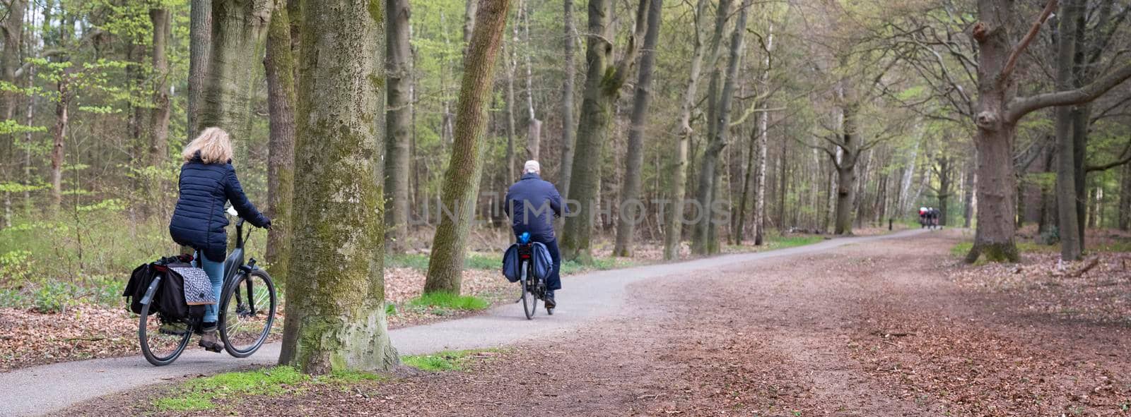 woman and man ride bicycle on bike track in the netherlands near utrecht on early spring day