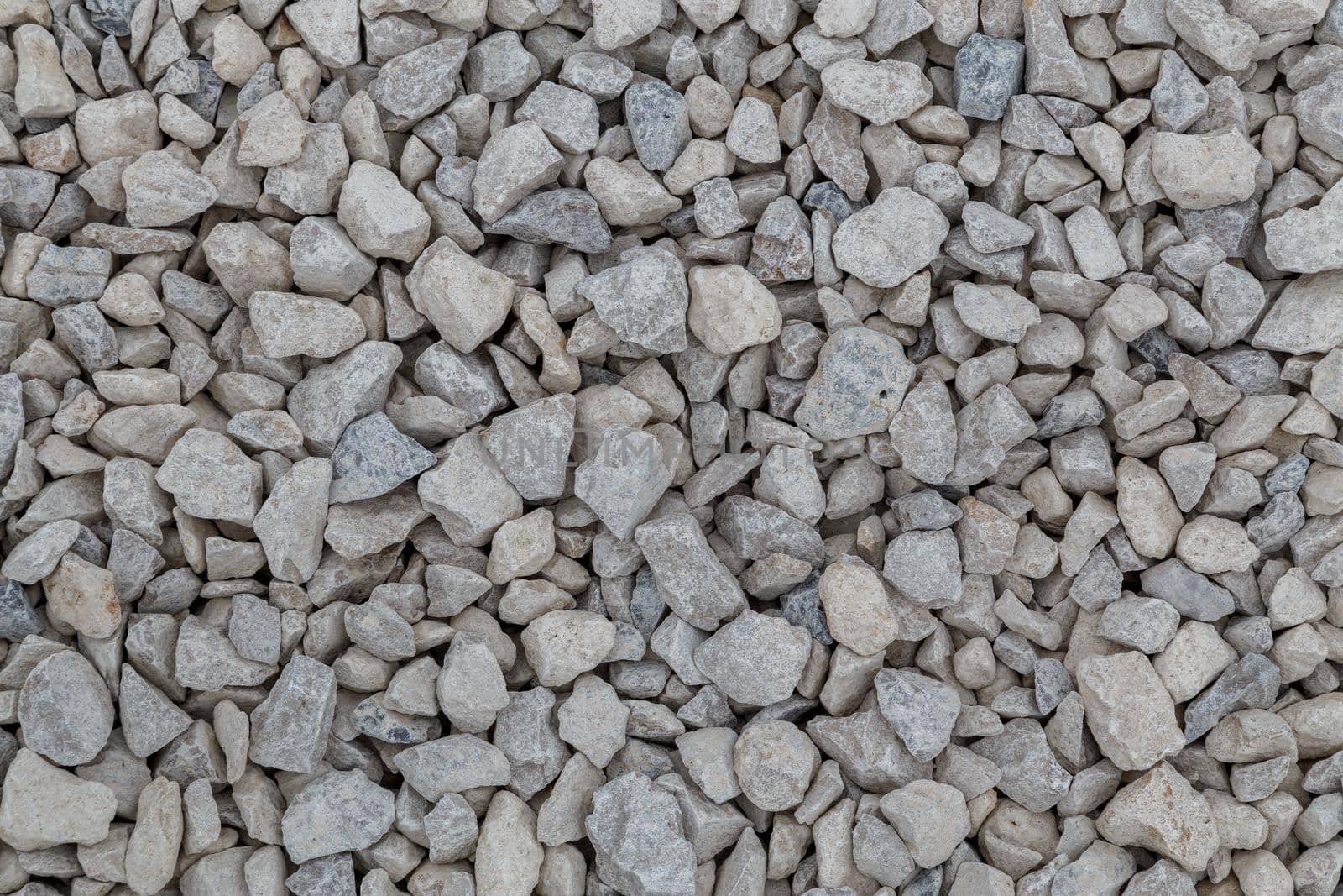 Dry white limestone ballast flat full frame background. Small gray dusty broken macadam stones texture. Viiew from above.