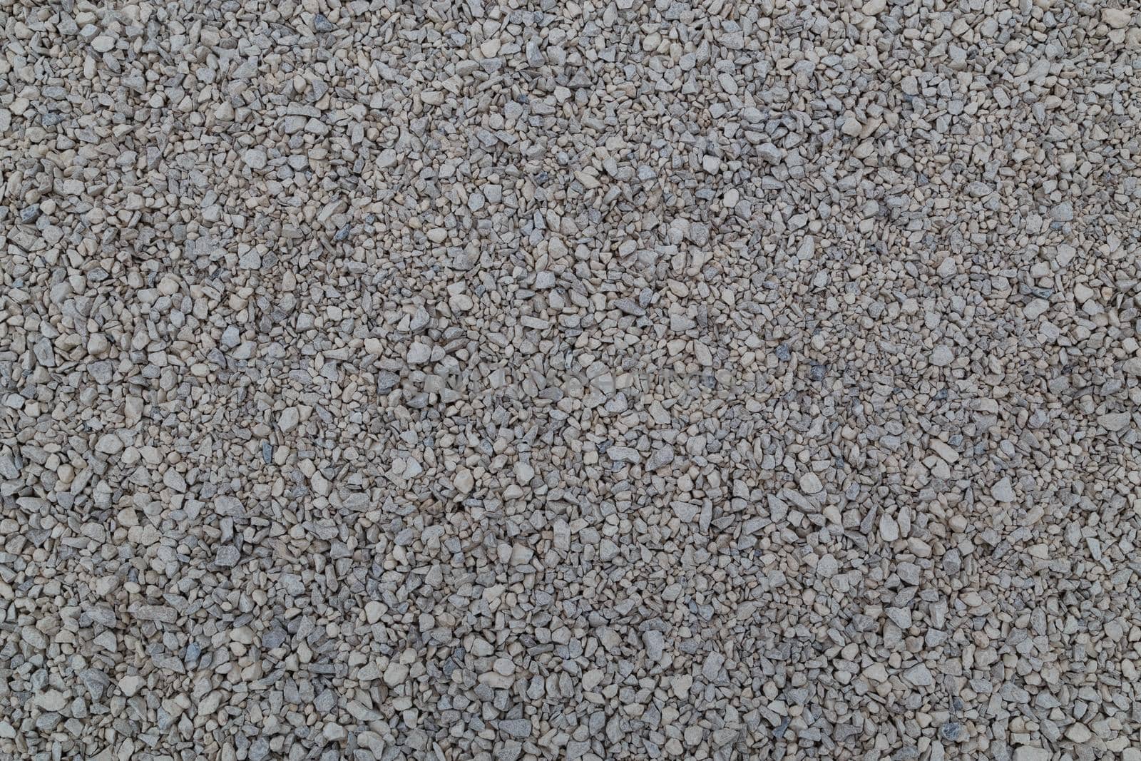 Dry white limestone ballast flat full frame background. Small gray dusty broken macadam stones texture. Viiew from above.