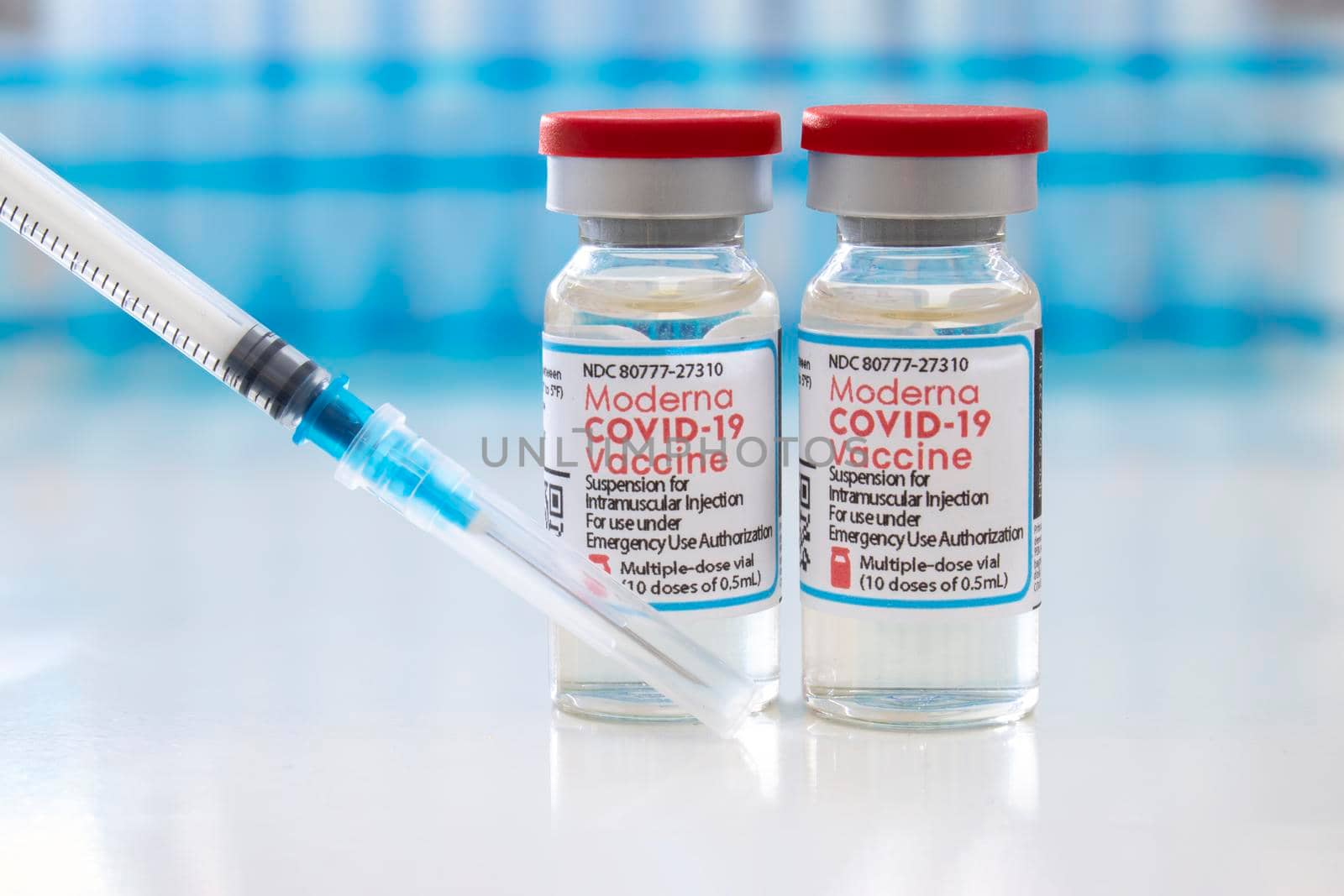 Calgary, Alberta, Canada. April 7, 2021. A couple of Moderna dosis of Covid-19 vaccines on vial bottles and an injection syringe. by oasisamuel
