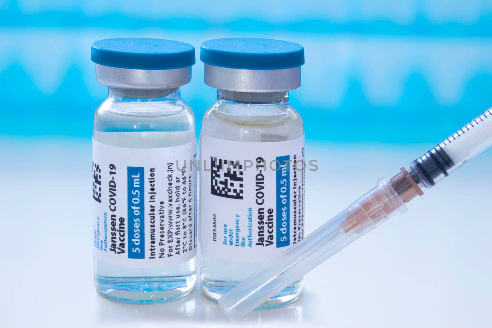 Calgary, Alberta, Canada. April 8, 2021. A couple of Janssen Johnson & Johnson dosis of Covid-19 vaccines on vial bottles and an injection syringe. by oasisamuel