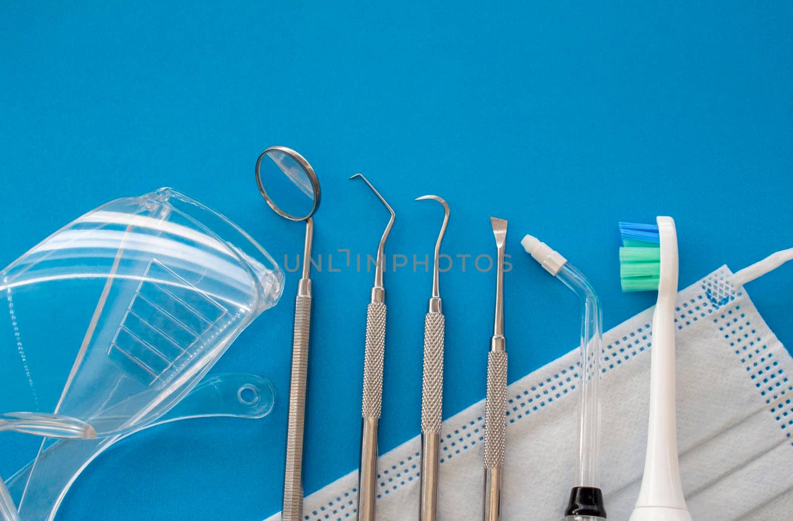 Dentist tools on blue surface close up. Professional Dental Hygiene cleaning tools. Calculus and Plaque Remover Set, Dental Scaler And Mouth Mirror Instruments Hygienist tools by oasisamuel