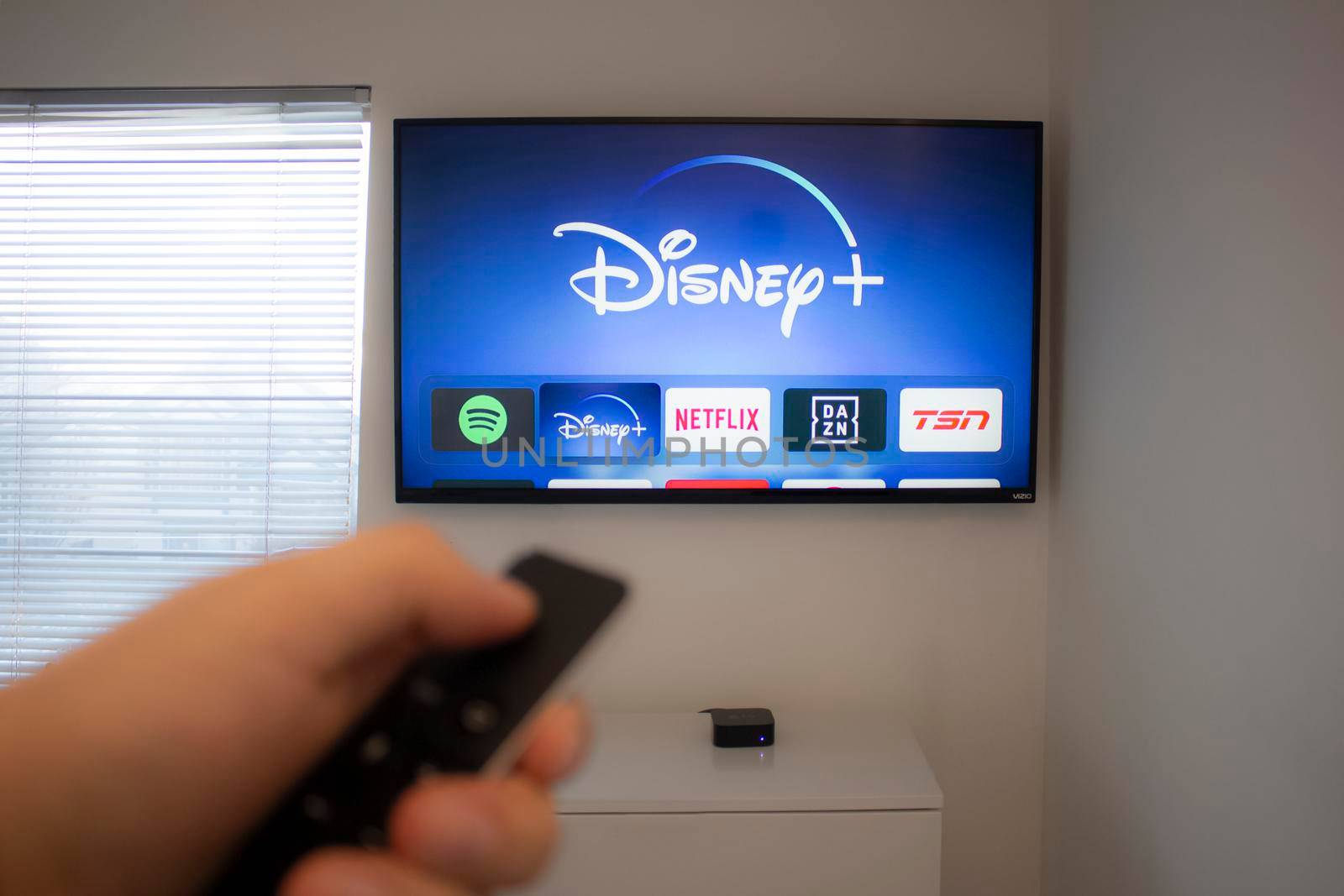 Calgary, Alberta. Canada Dec 5 2019: Person holds an Apple TV remote using the new Disney+ app on a Vizio TV. Disney+ video streaming service will exclusively show Star Wars: Jedi Template Challenge. by oasisamuel