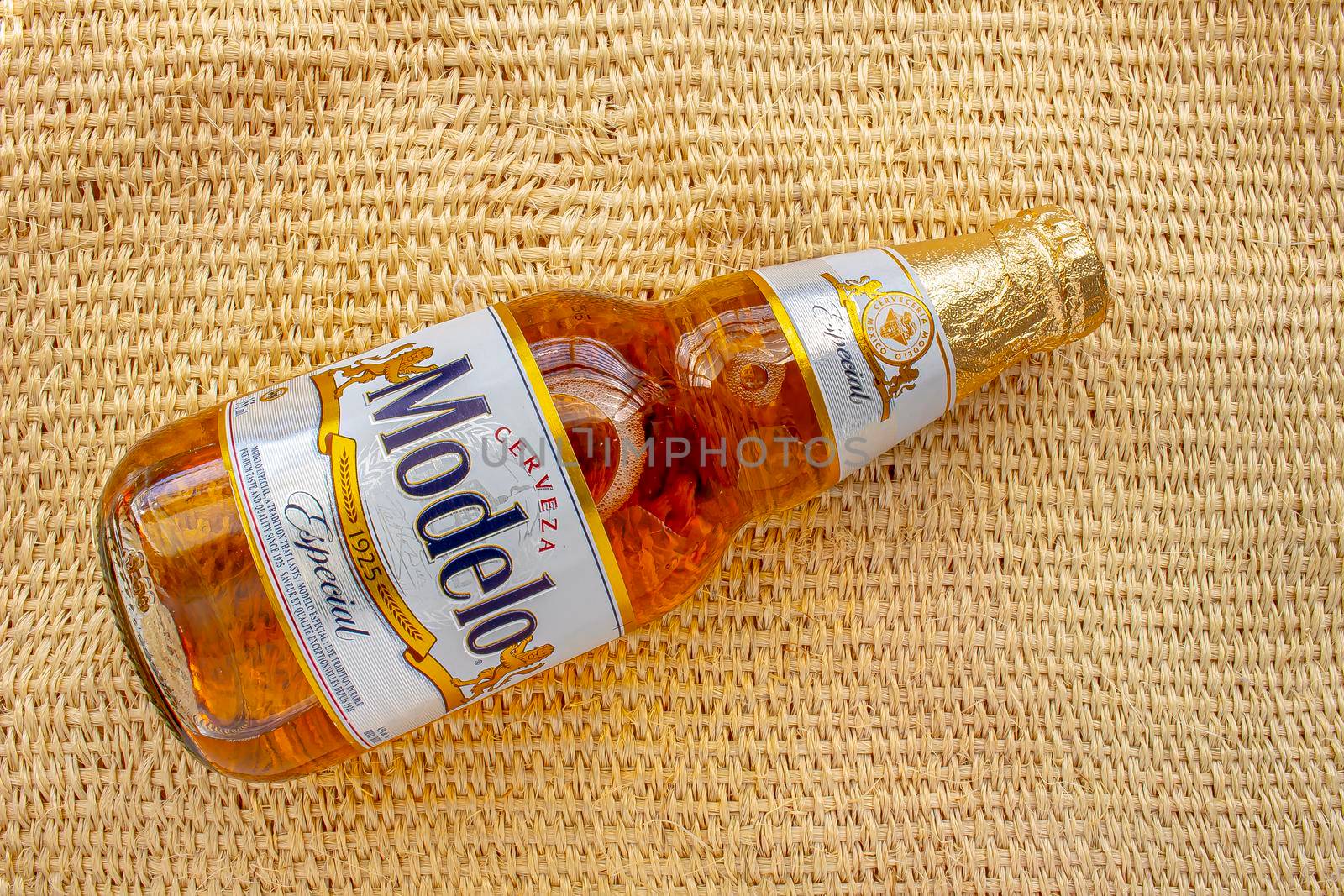 Calgary, Alberta, Canada. May 1, 2020. Modelo Especial beer bottle clear bright yellow colour on a on a straw rural bag background texture