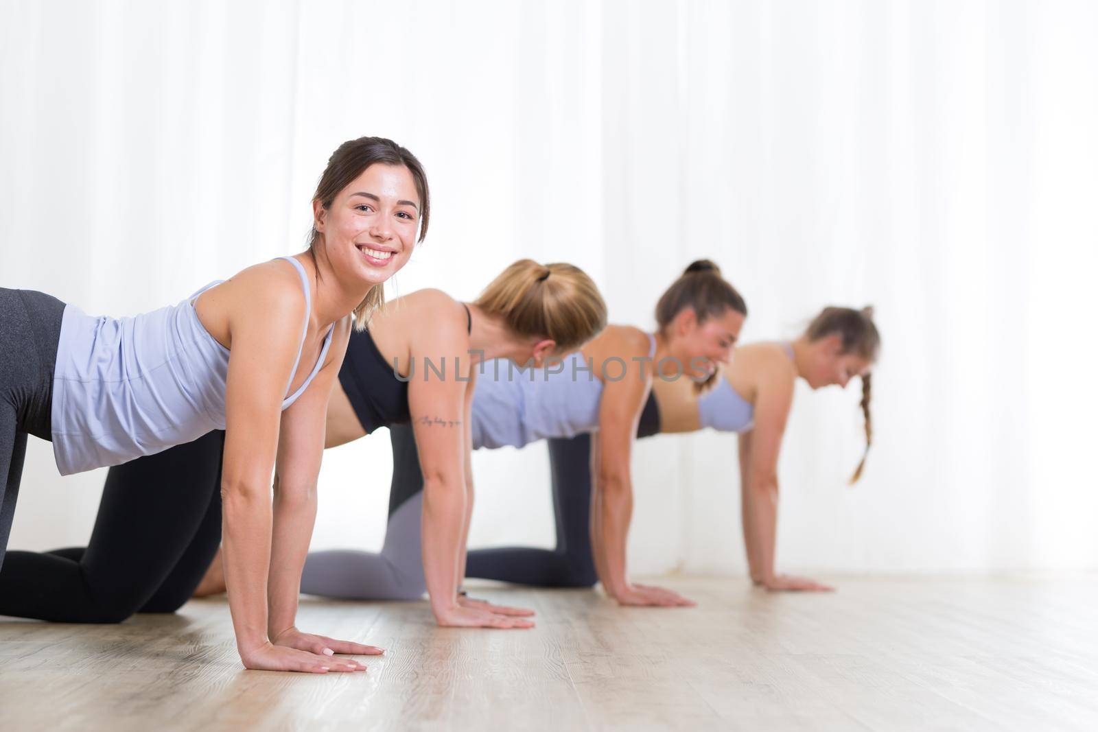 Group of young sporty women in yoga studio, practicing yoga. Healthy active lifestyle, working out indoors in gym.