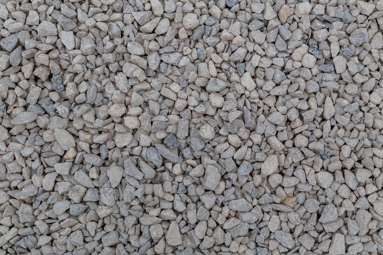 Dry white limestone ballast flat full frame background. Small gray dusty broken macadam stones texture. Viiew from above.