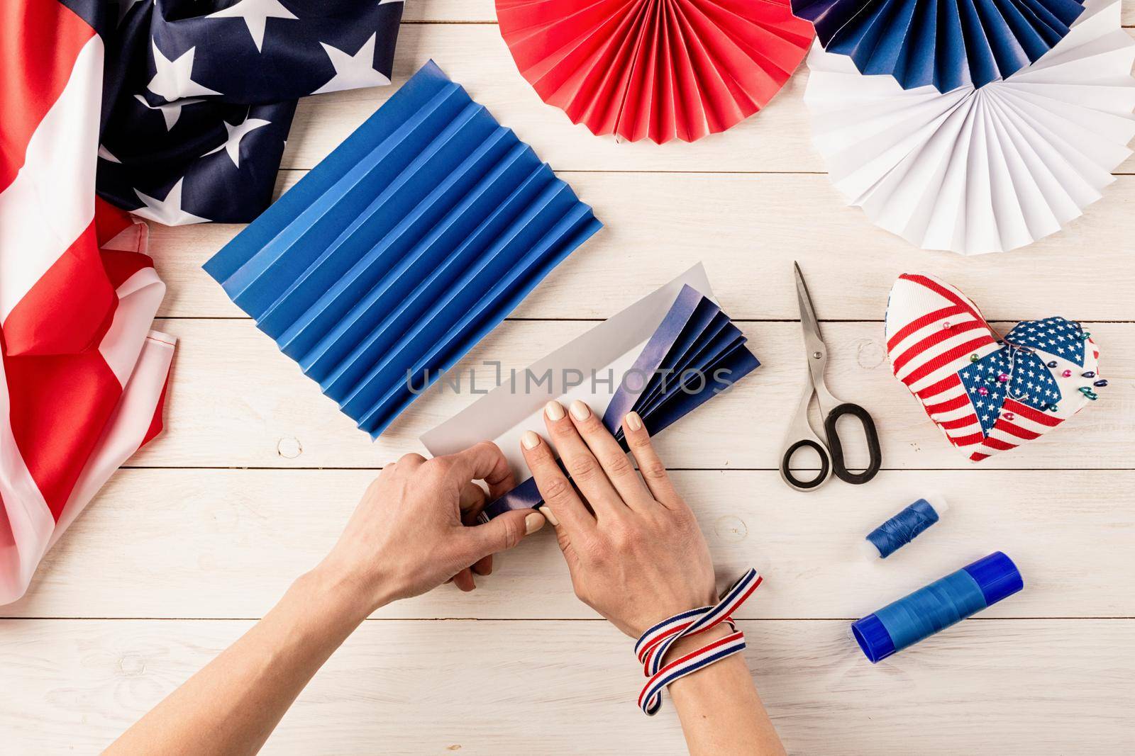 Gift idea, decor July 4, USA Independence Day. Step by step tutorial DIY craft. Making colorful paper fans, step 3 - folding the rest of paper. Flat lay top view