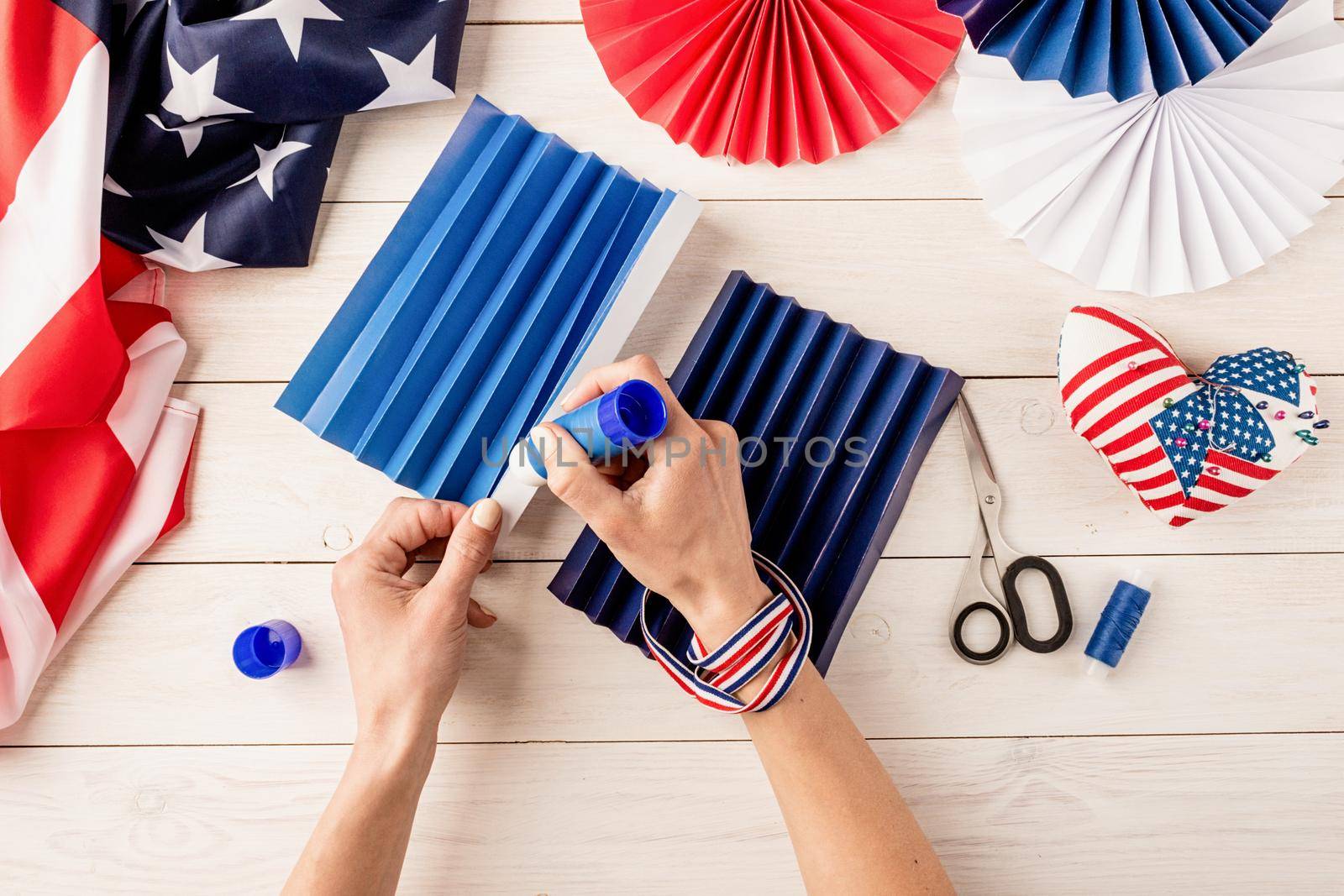 Gift idea, decor July 4, USA Independence Day. Step by step tutorial DIY craft. Making colorful paper fans, step 4 - gluing paper, stick together. Flat lay top view