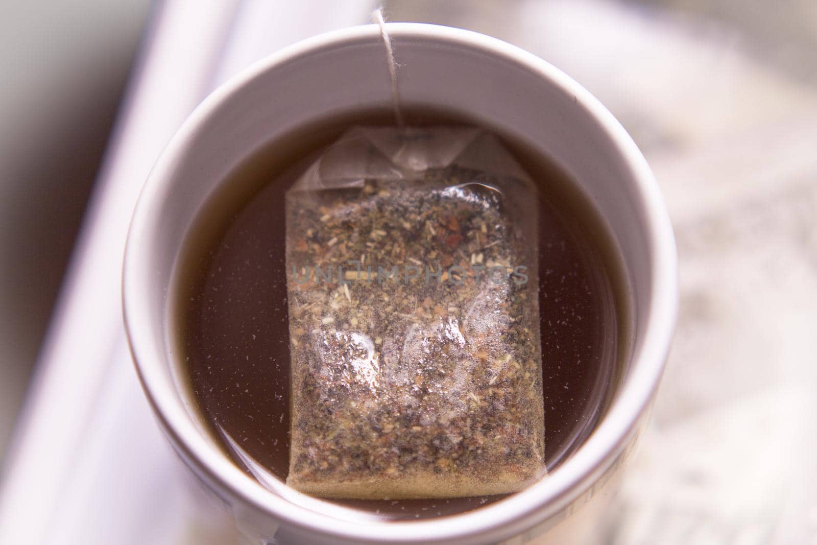 White cup with infusion and tea bag. No people