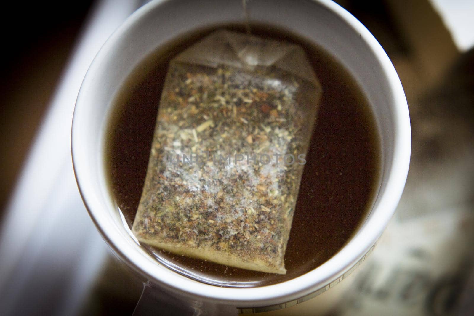 White cup with infusion and tea bag. No people