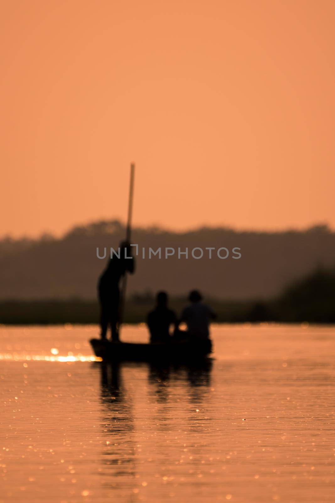 Blurred Men in a boat on a river silhouette with sunset light. Artistic blur