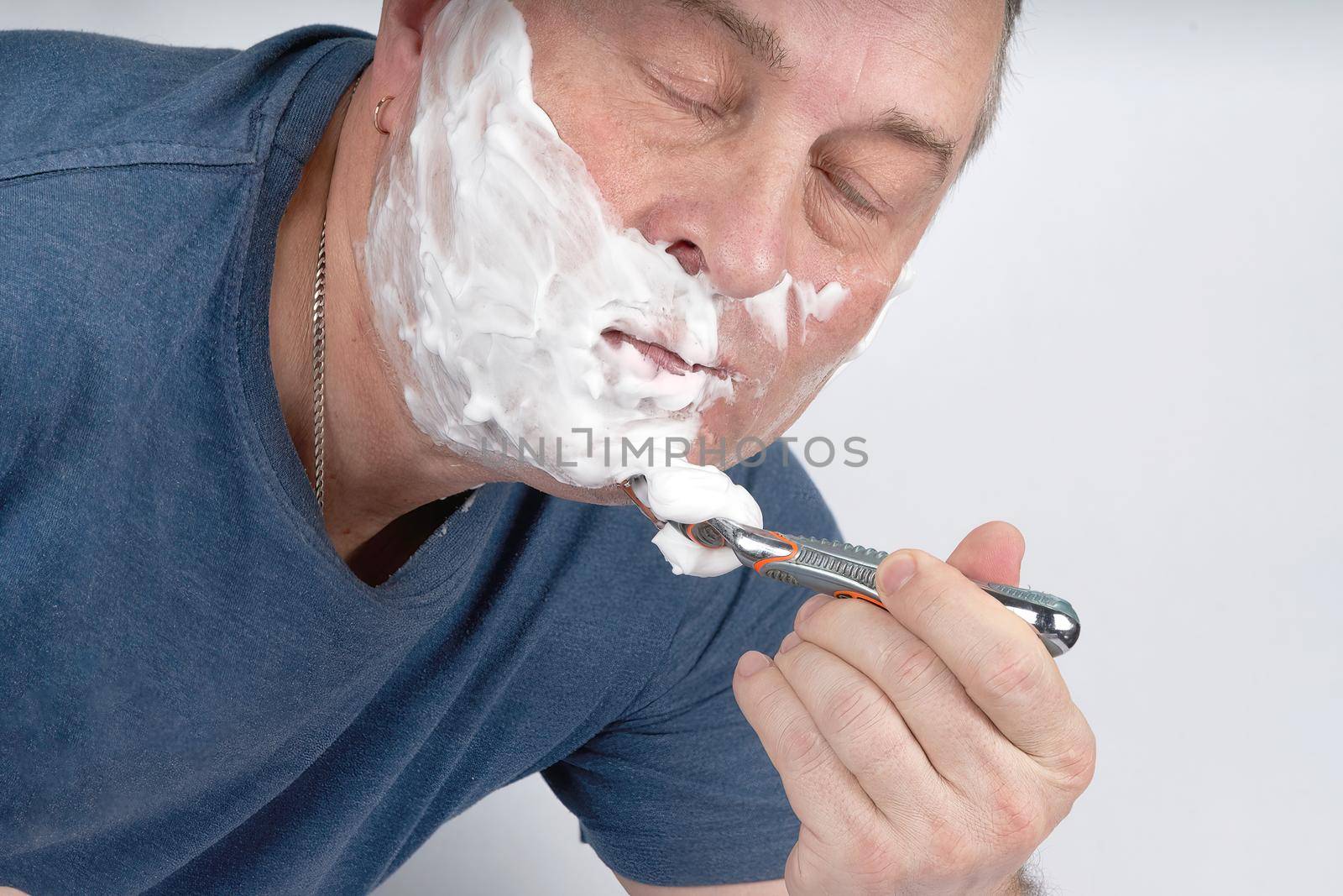 Man closing his eyes shaves with a safety razor. Morning or evening exercise, personal hygiene