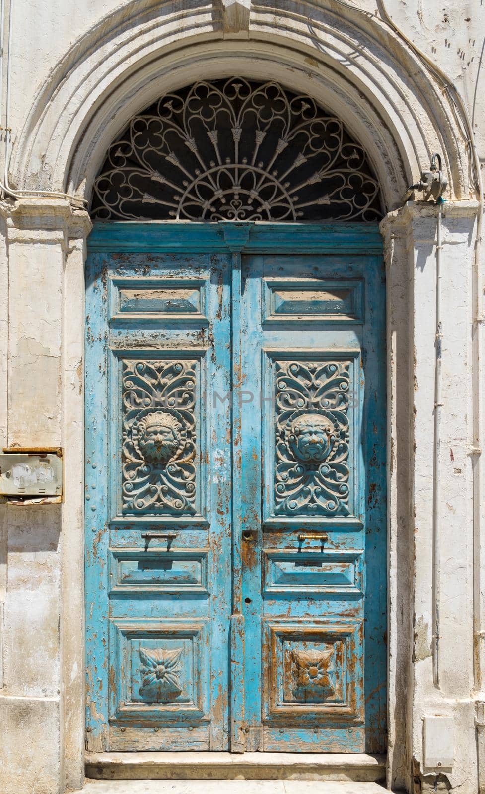 Blue aged Tunisian wooden door with arch and ornament. Culture and architecture of Tunisia