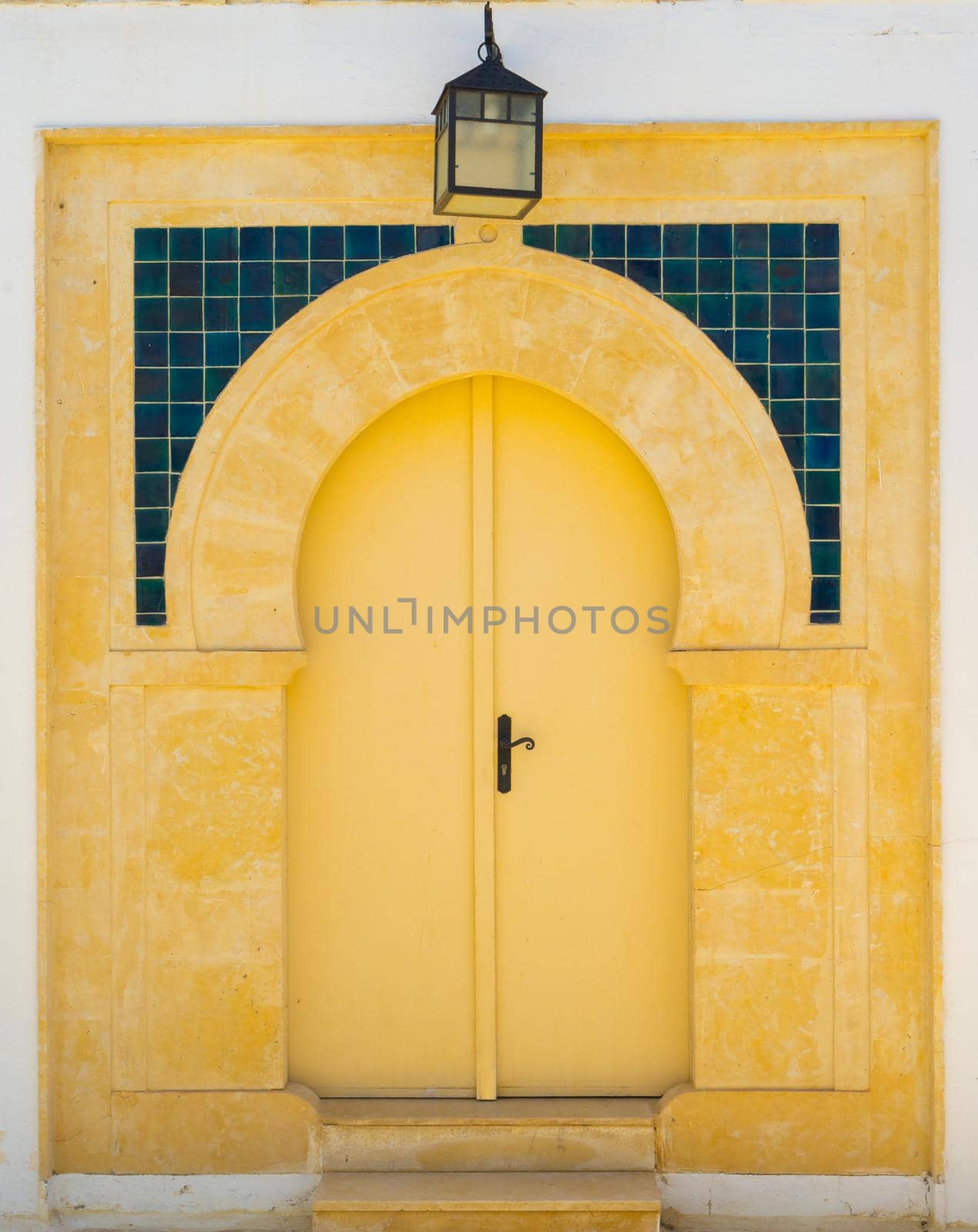 Yellow door with ornament and lantern from Sidi Bou Said in Tunisia. Culture of Tunisia