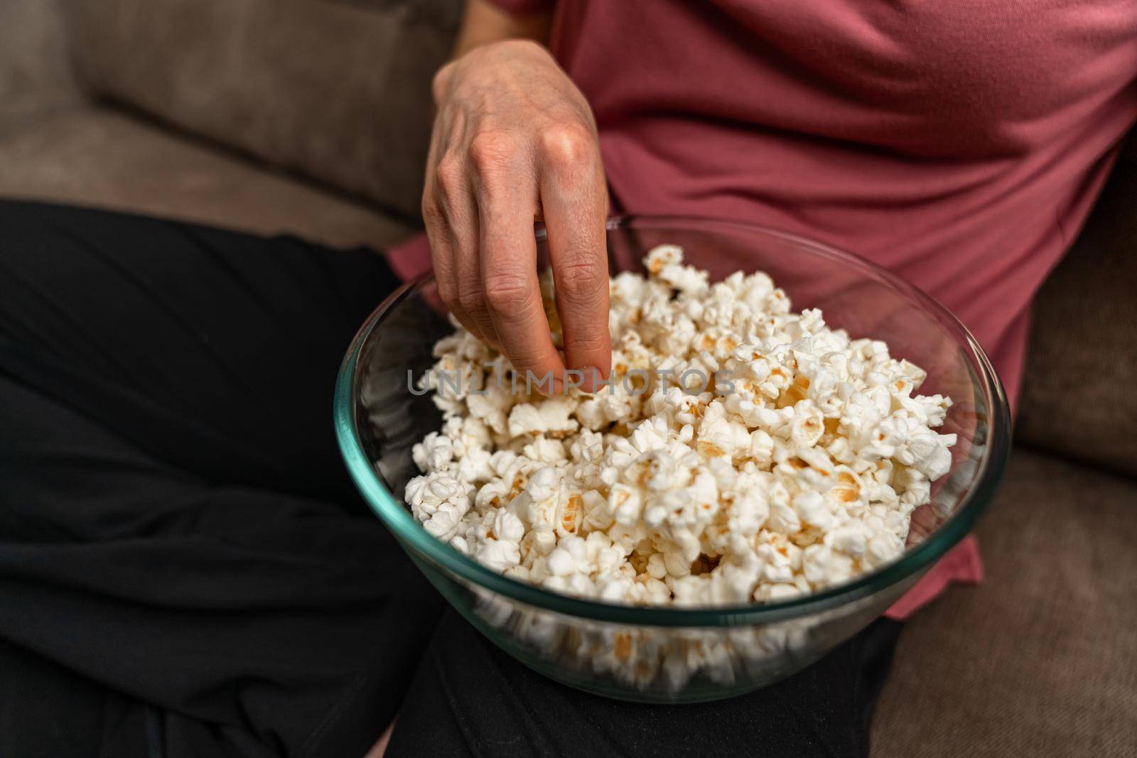 popcorn while watching a movie and broadcasting on the couch at home by Edophoto