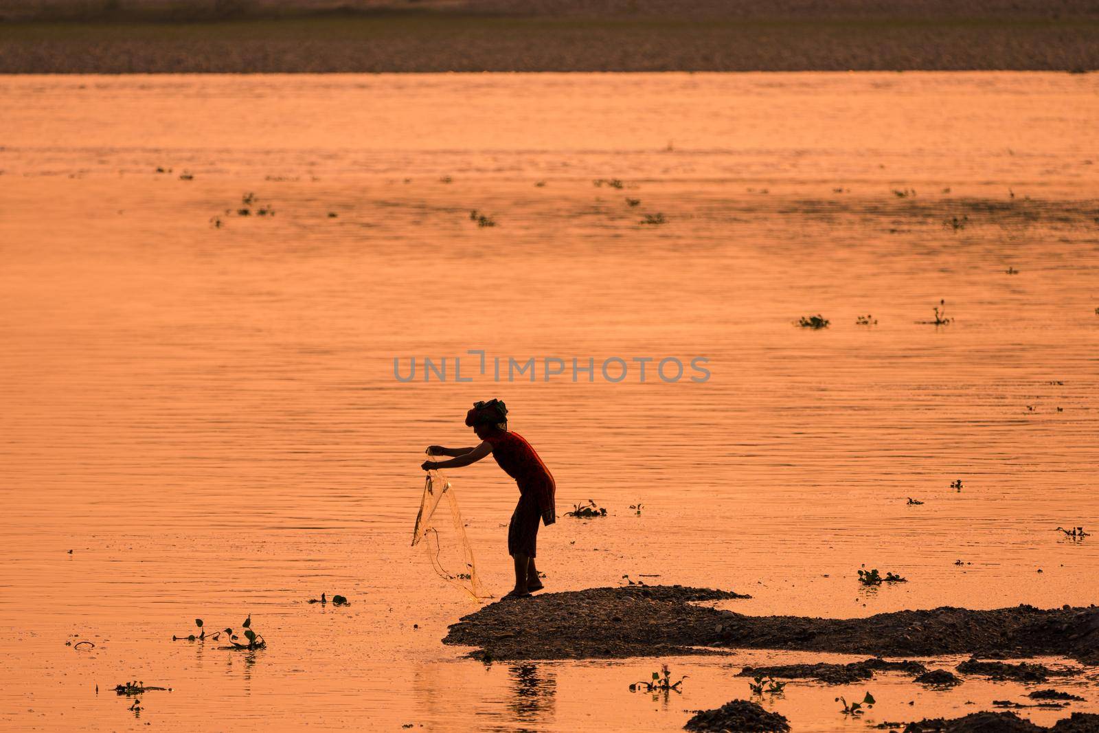 Asian Woman fishing in the river. silhouette at sunset. Village life in Asia