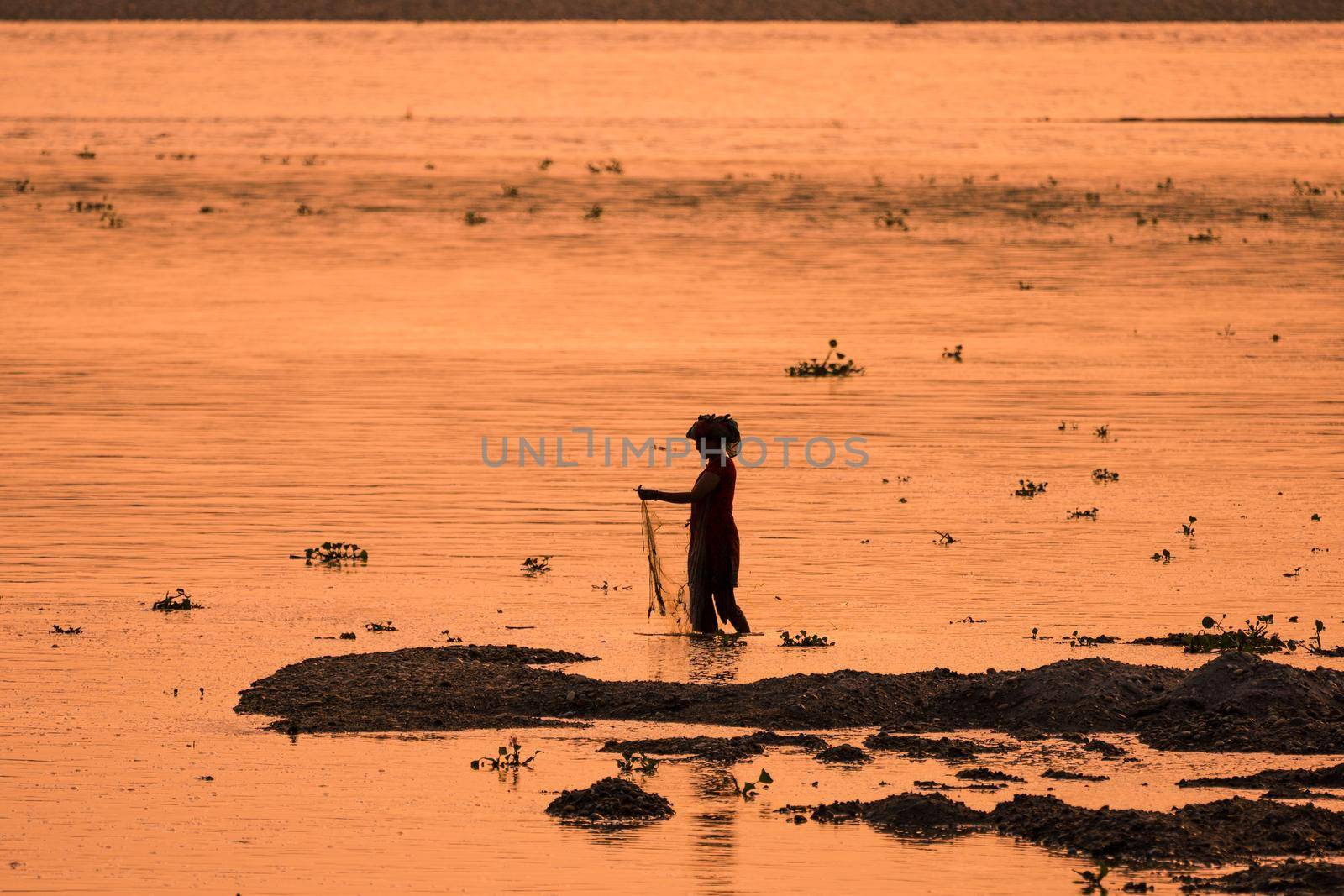 Asian Woman fishing in the river. silhouette at sunset. Village life in Asia