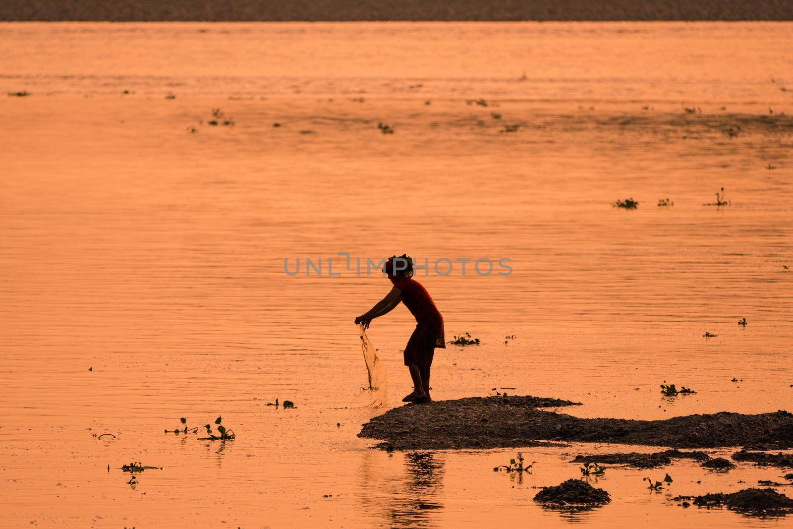 Asian Woman fishing in the river, silhouette at sunset by Arsgera