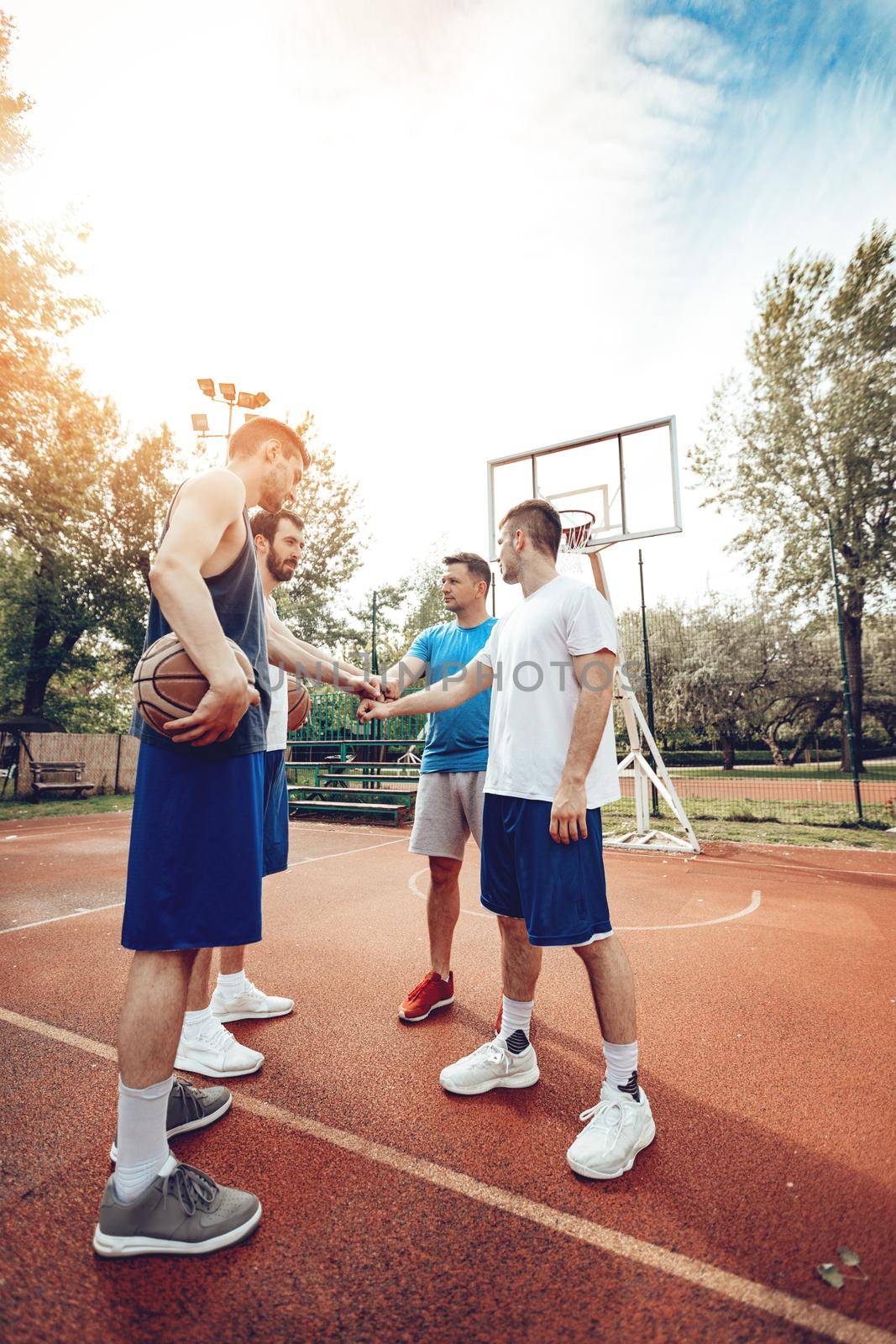 Four basketball players having a sports greeting before training. They hit their fists with smile on their face.