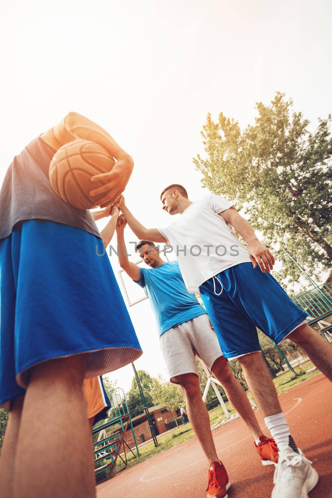 Four basketball players having a sports greeting before training. They hit their fists.