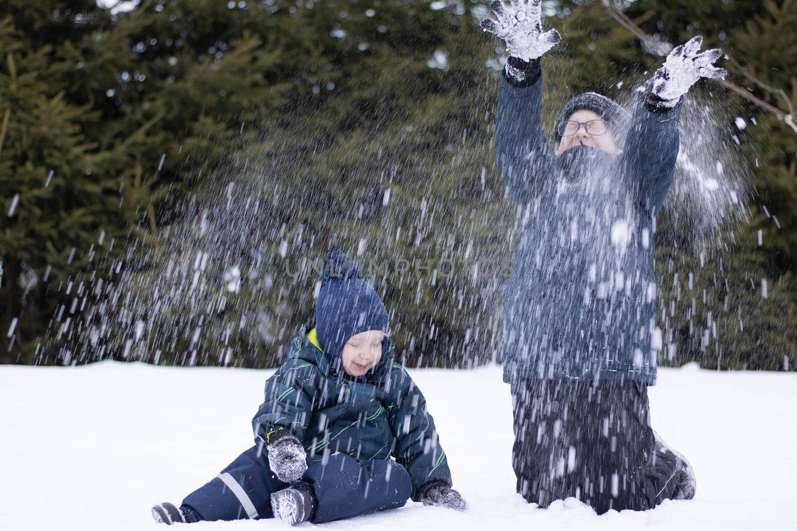 Winter fun, children play with snow, throwing it up, faces out of focus. by Sonluna