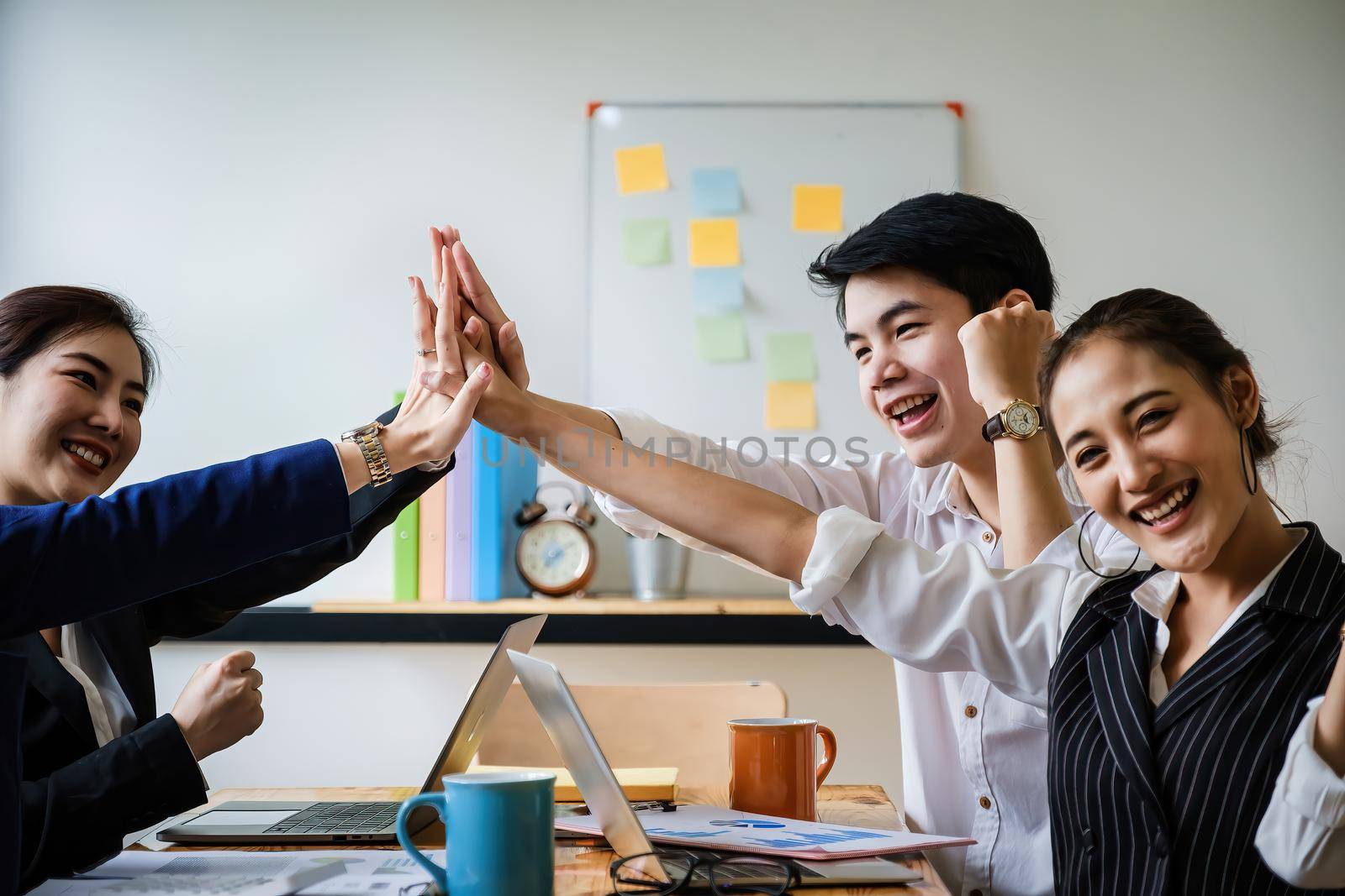 Business team giving a high fives gesture as they laugh and cheer their success. Achievement and Business Goal Success Concept. soft focus