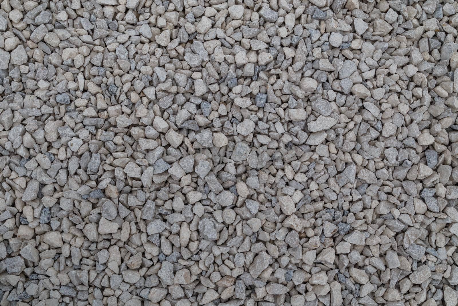 Dry white limestone ballast flat full frame background. Small gray dusty broken macadam stones texture. Viiew from above.