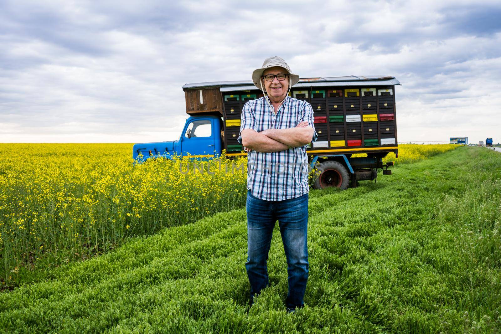 Proud beekeeper is standing in front of his truck with beehives.