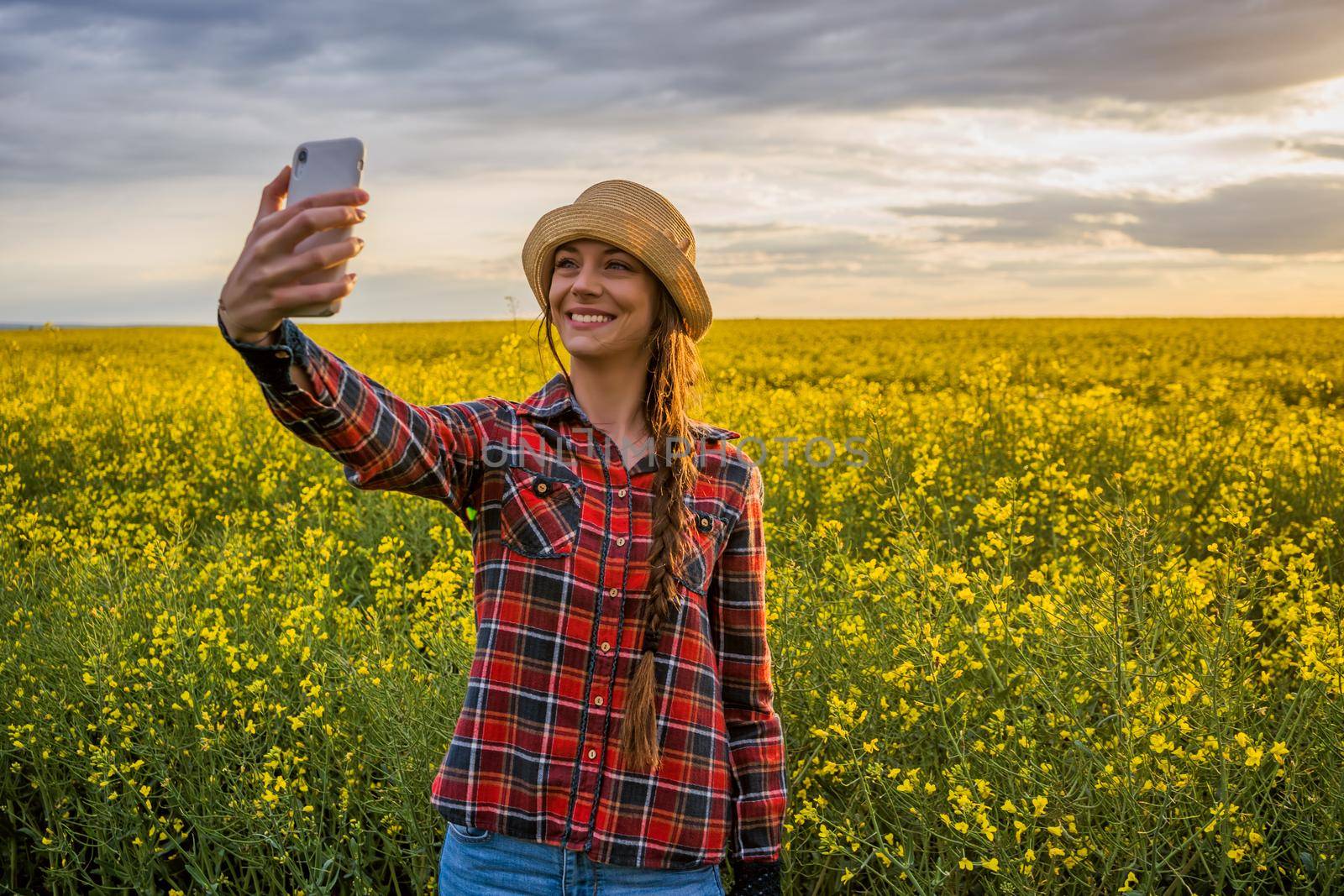 Proud female farmer is taking selfie in front of her rapeseed field.