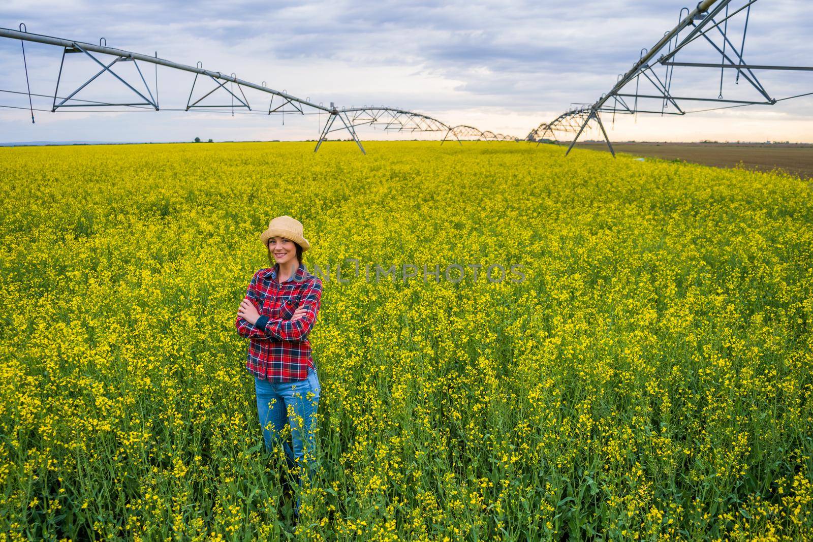 Proud female farmer is standing in her rapeseed field.