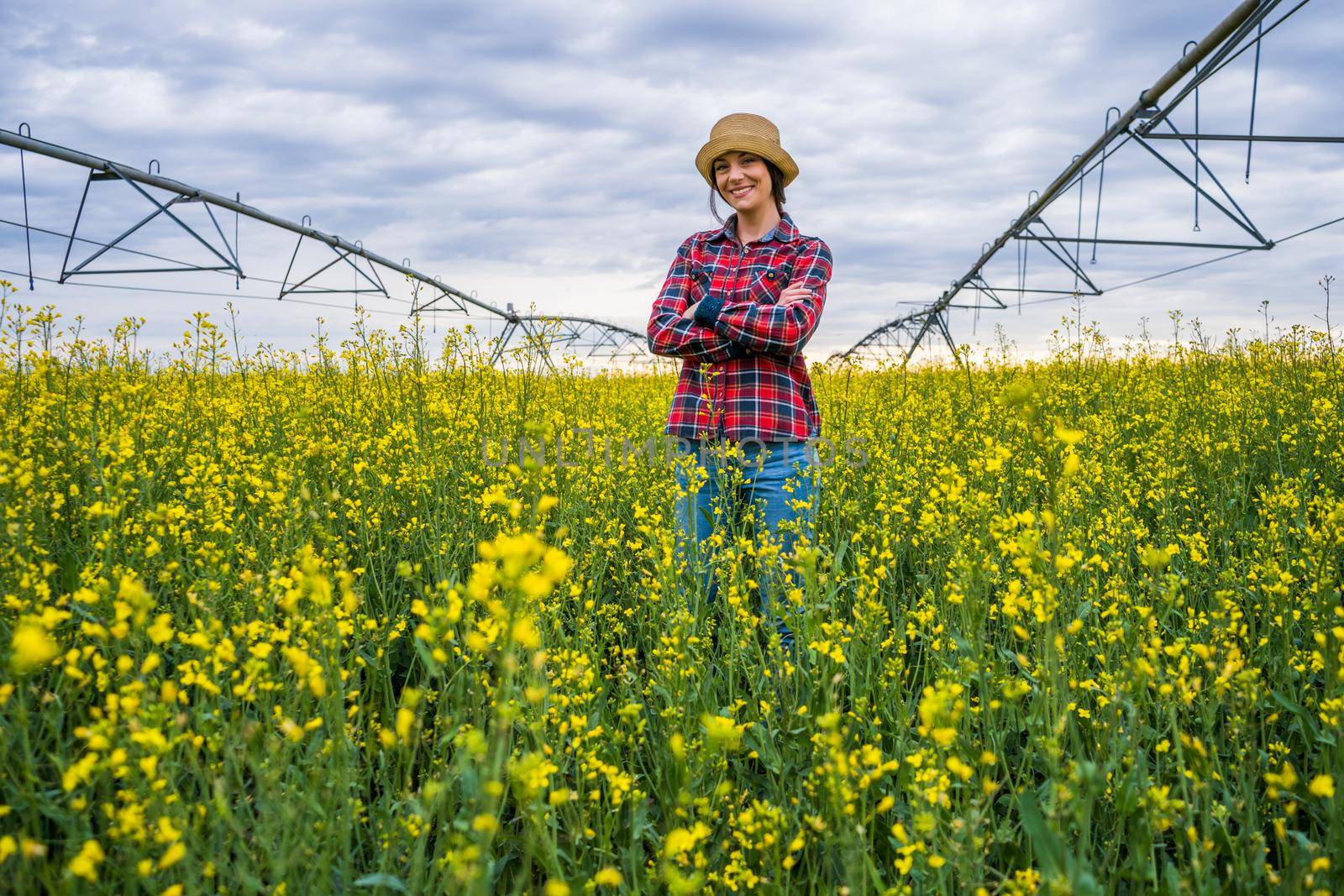 Proud female farmer is standing in her rapeseed field.