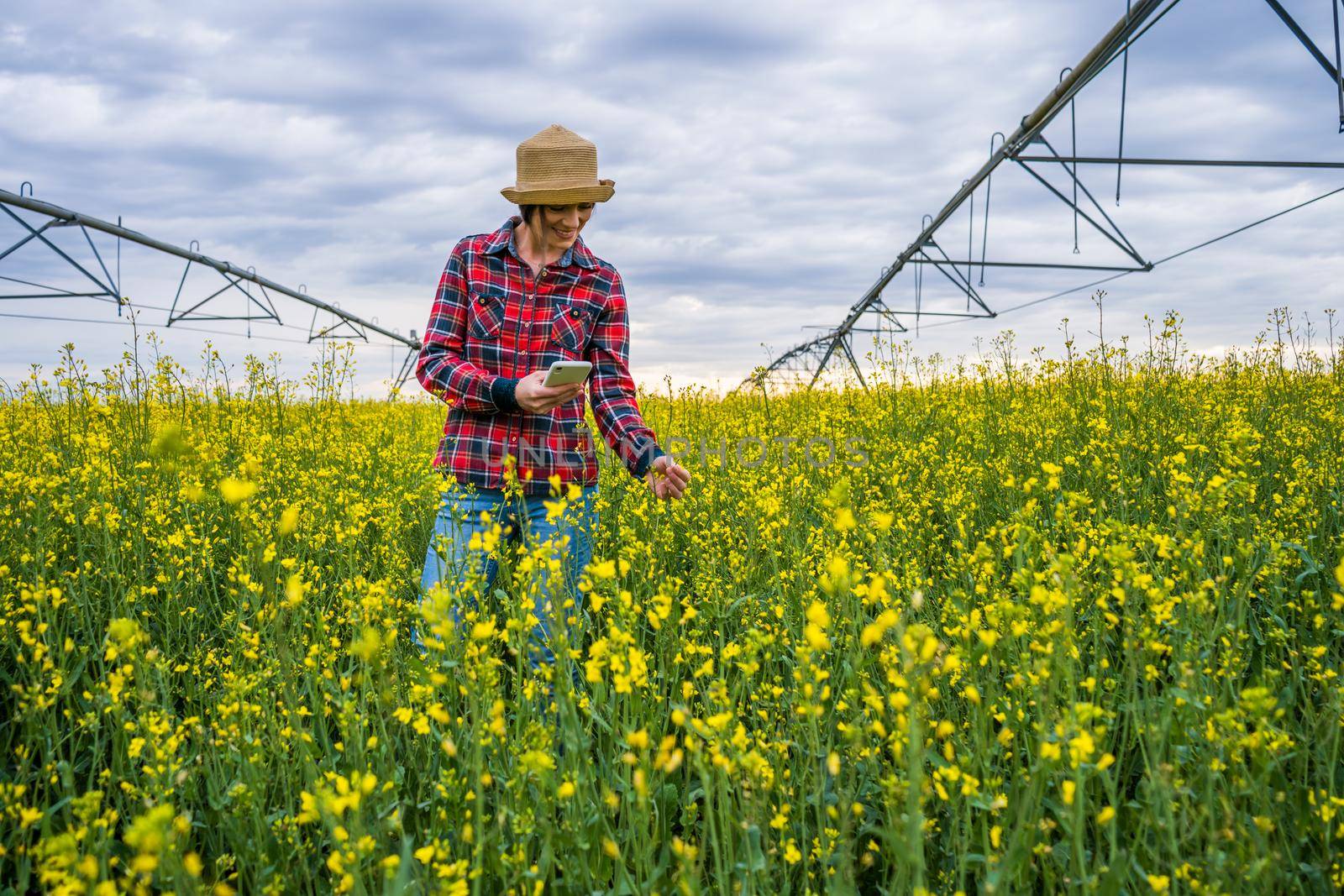 Proud female farmer is standing in her rapeseed field.